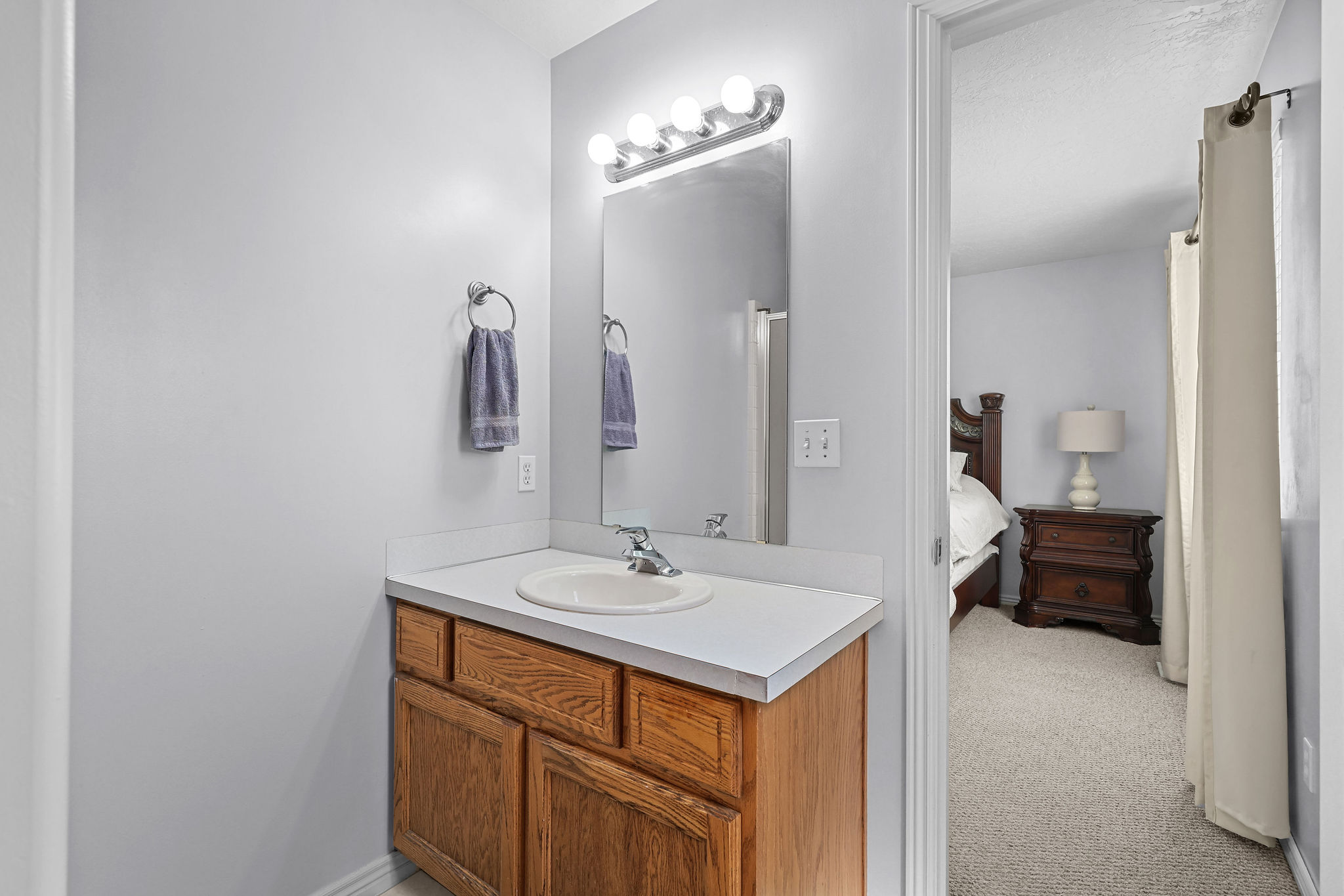 Bathroom vanity featuring a light wood-finish cabinet with white countertop and integrated sink