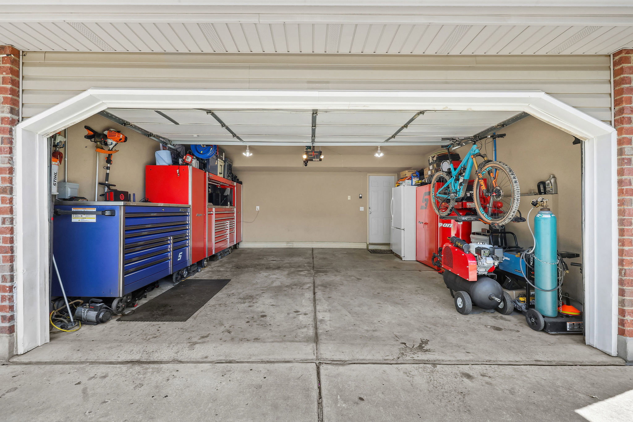 Spacious attached garage with concrete flooring, finished walls, and overhead lighting
