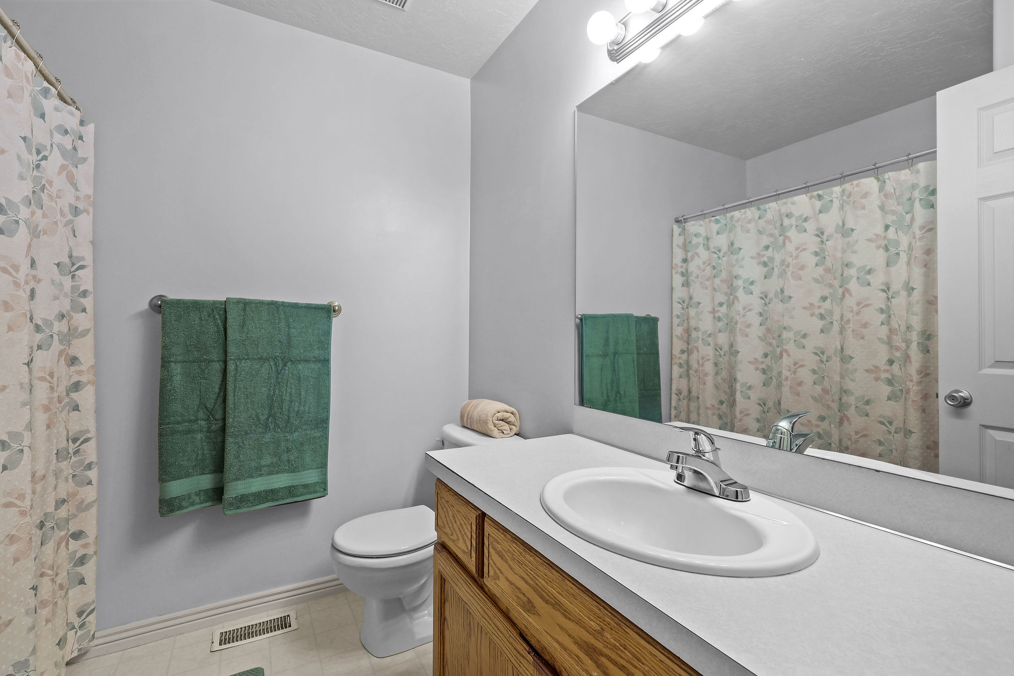 Bathroom featuring a single vanity with wood-finish cabinetry, a white countertop, and an integrated sink