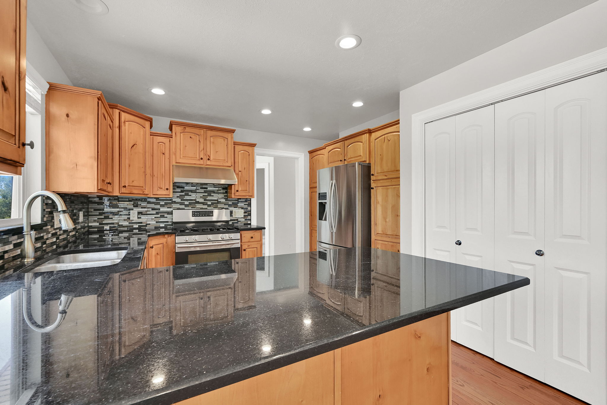 Kitchen featuring granite-look countertops, wood cabinetry, stainless steel appliances, and a mosaic tile backsplash