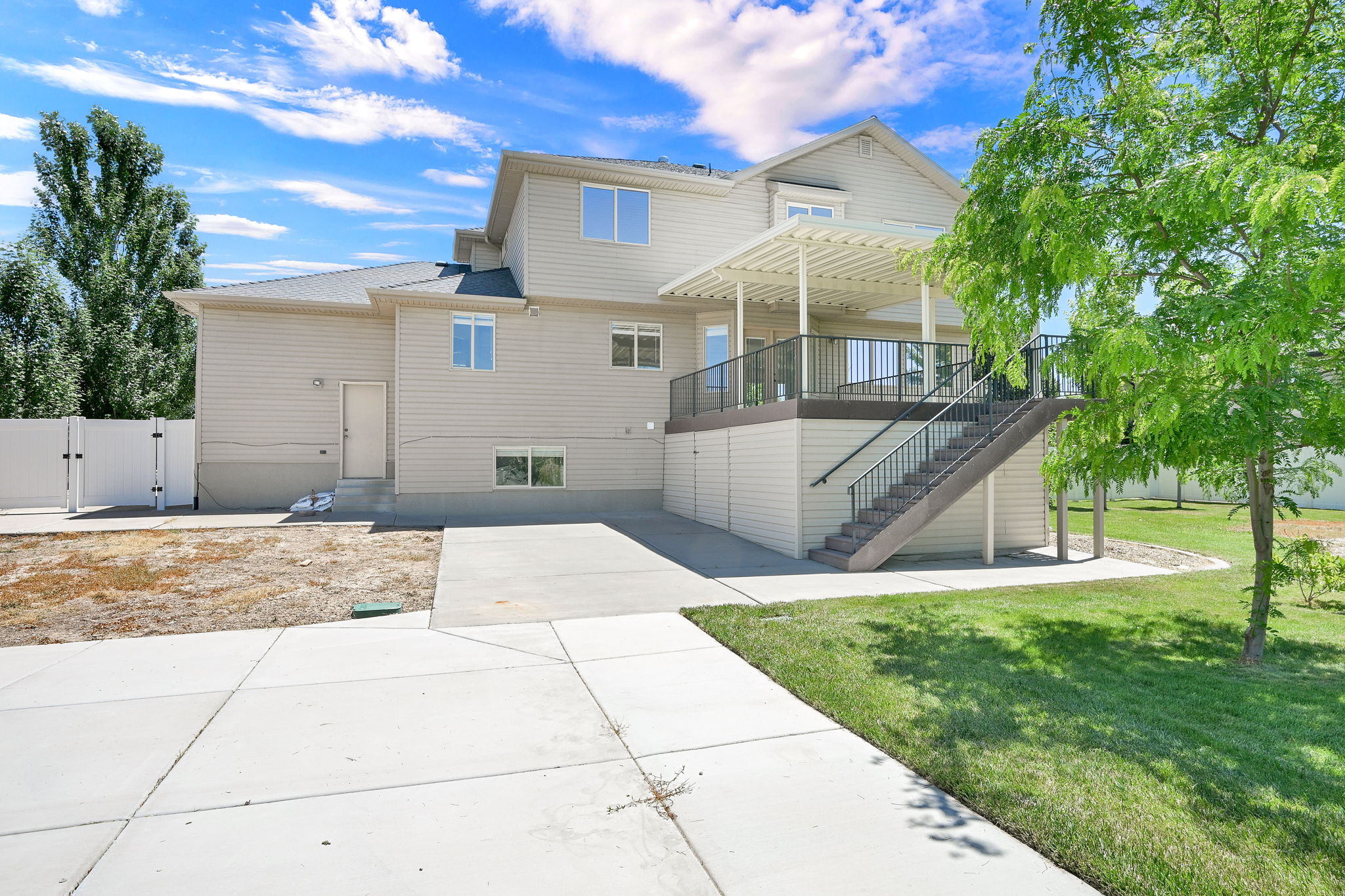 Rear exterior featuring an elevated deck with a pergola, exterior staircase, and concrete patio