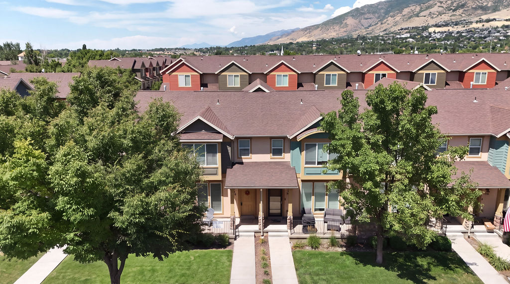 Multi-story townhomes featuring varied exterior finishes, individual covered entrances, and front patios