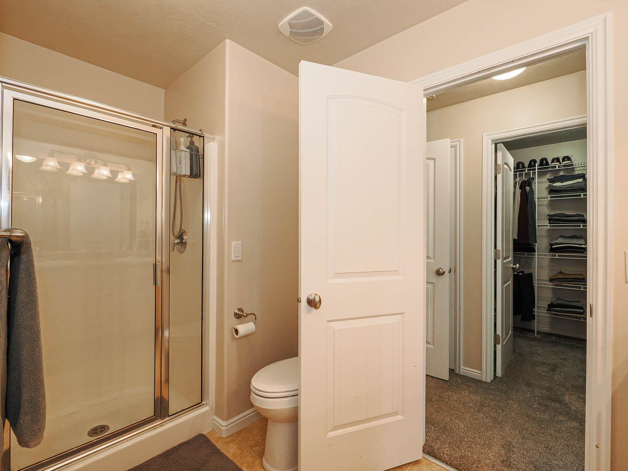 Shower enclosure with sliding glass doors, overhead light fixture, and a toilet