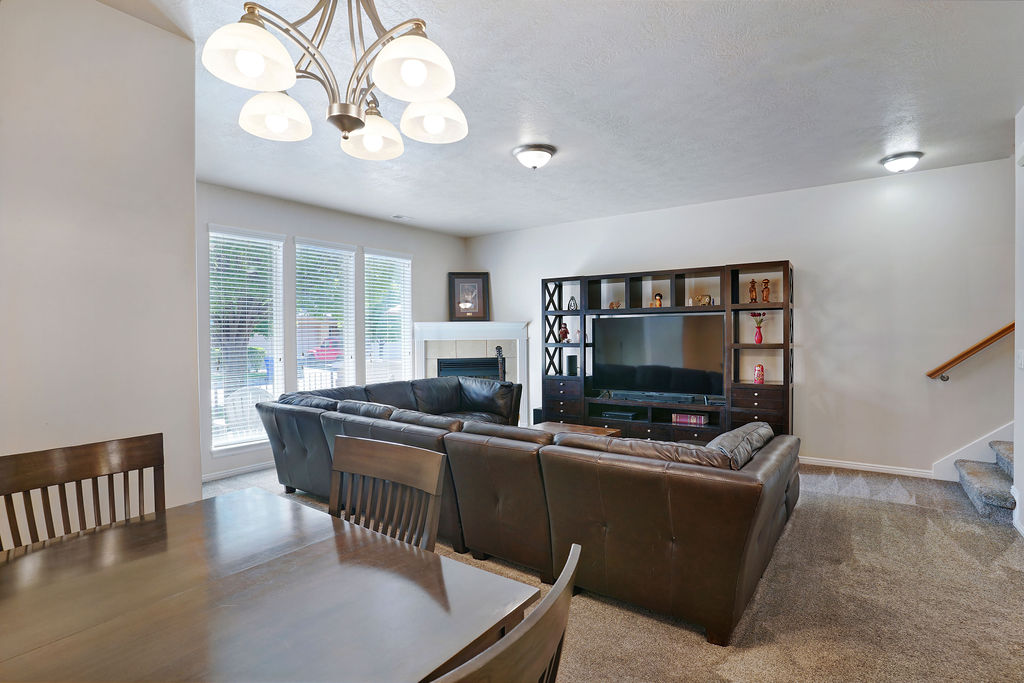 Open-concept living area featuring a fireplace with a white mantel, multiple large windows, and a built-in media console
