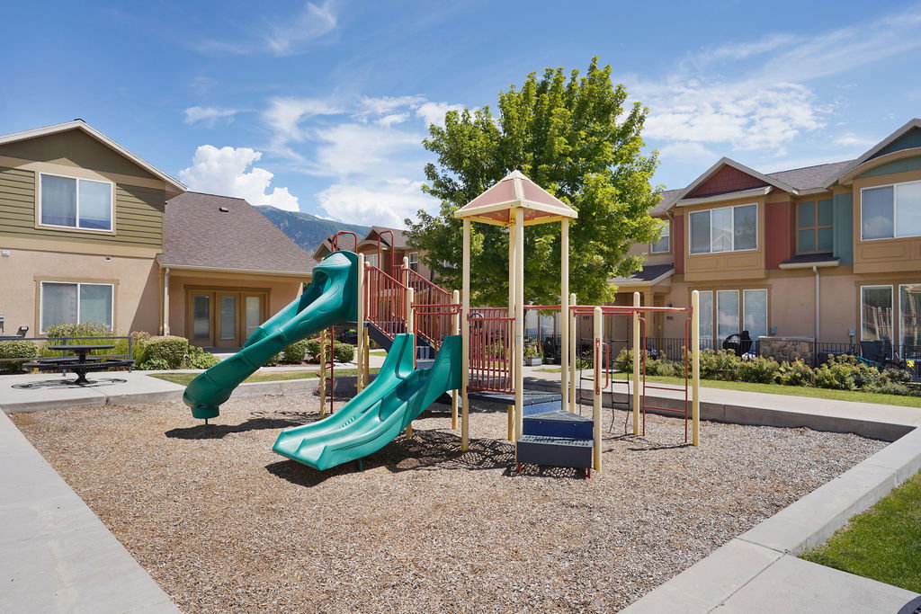 Recreational playground structure featuring two green slides, monkey bars, and a climbing platform