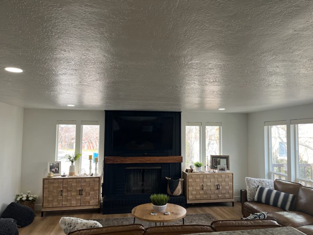 Living area featuring wood-finish flooring, recessed ceiling lighting, a dark brick fireplace with a wood mantel, and multiple windows