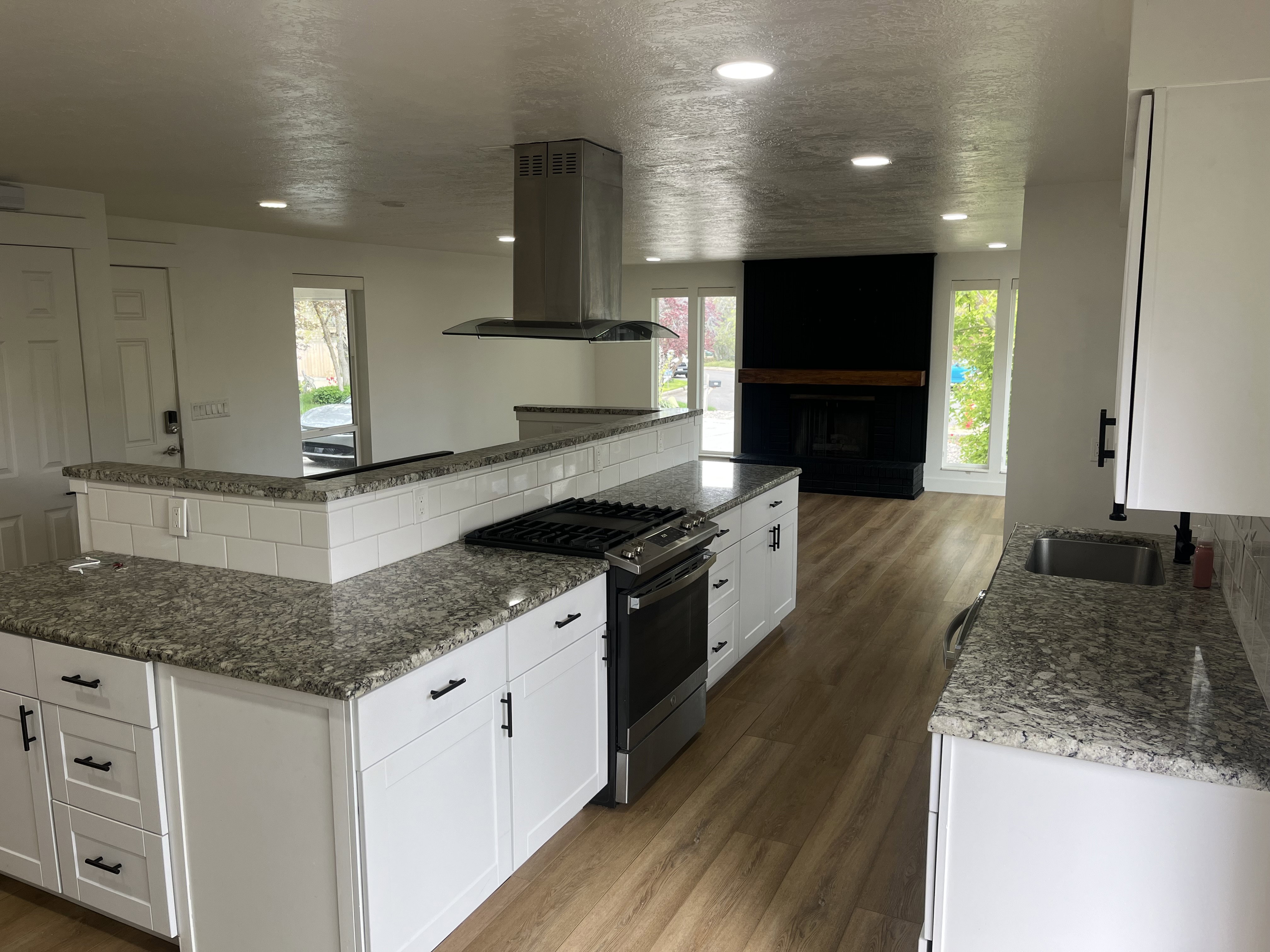 Kitchen featuring light wood-finish flooring, white cabinetry with black hardware, and granite countertops