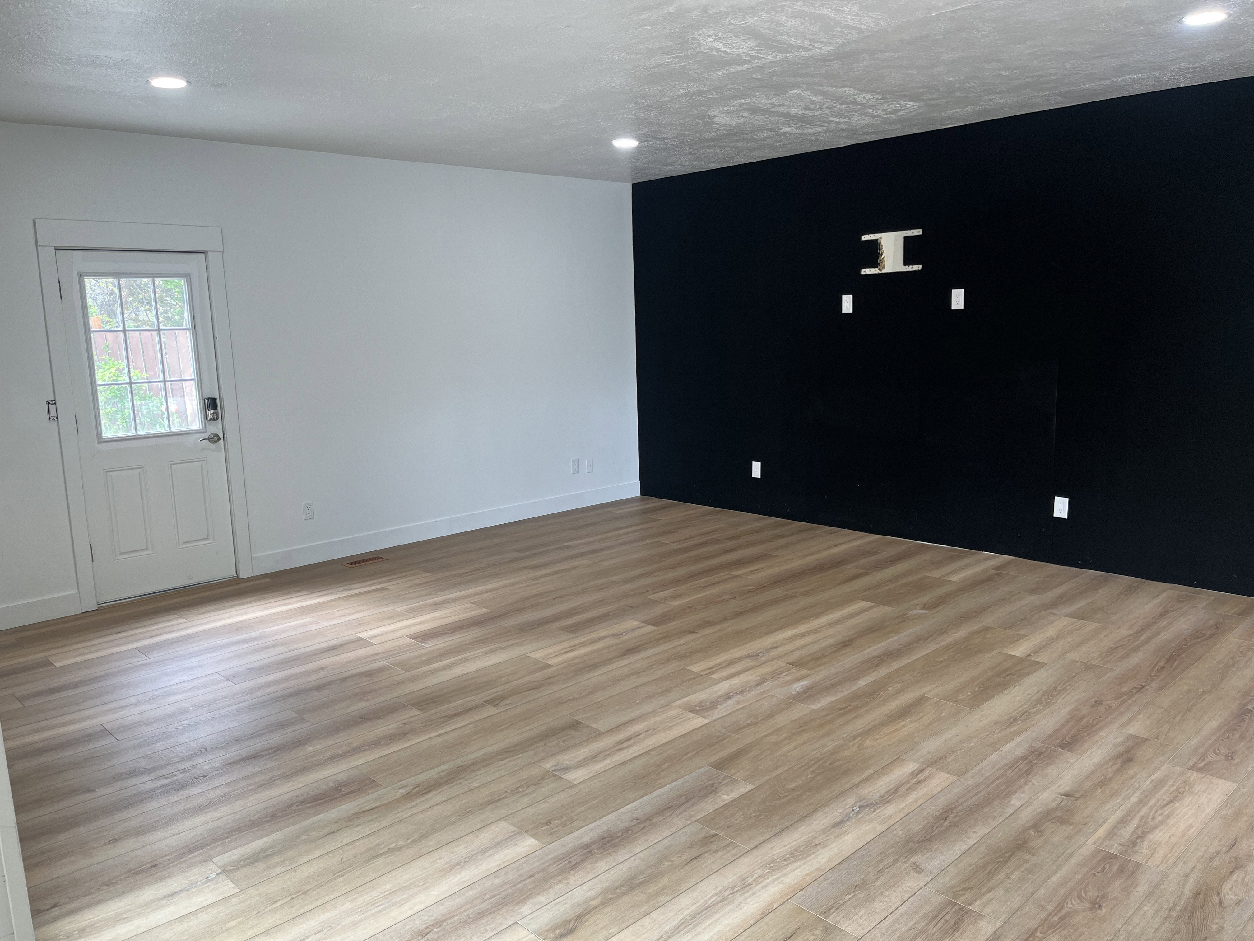 Spacious room featuring wood-finish flooring, recessed lighting, and a contrasting accent wall with built-in media wiring