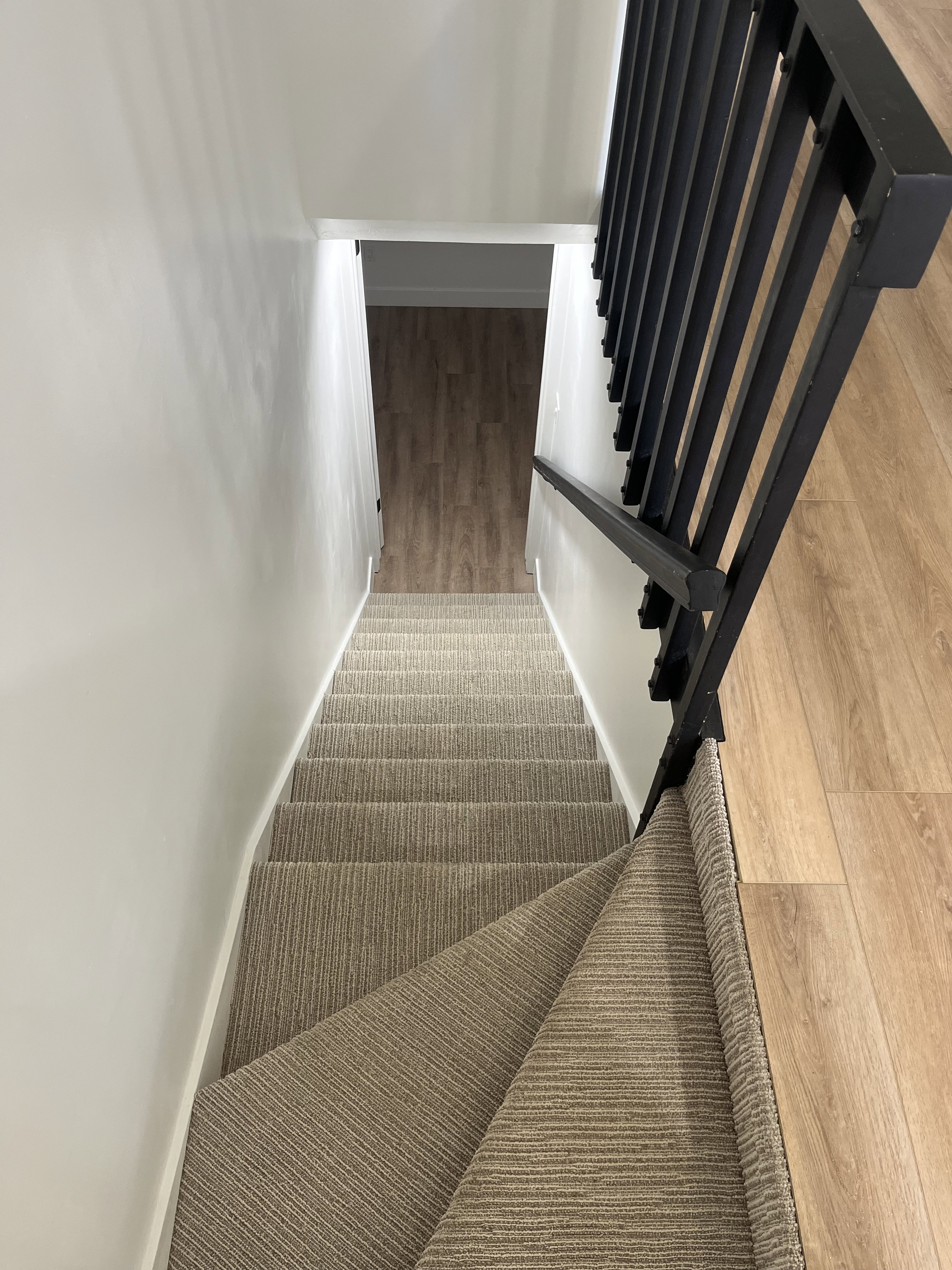 Carpeted staircase with contemporary black metal balusters and handrail