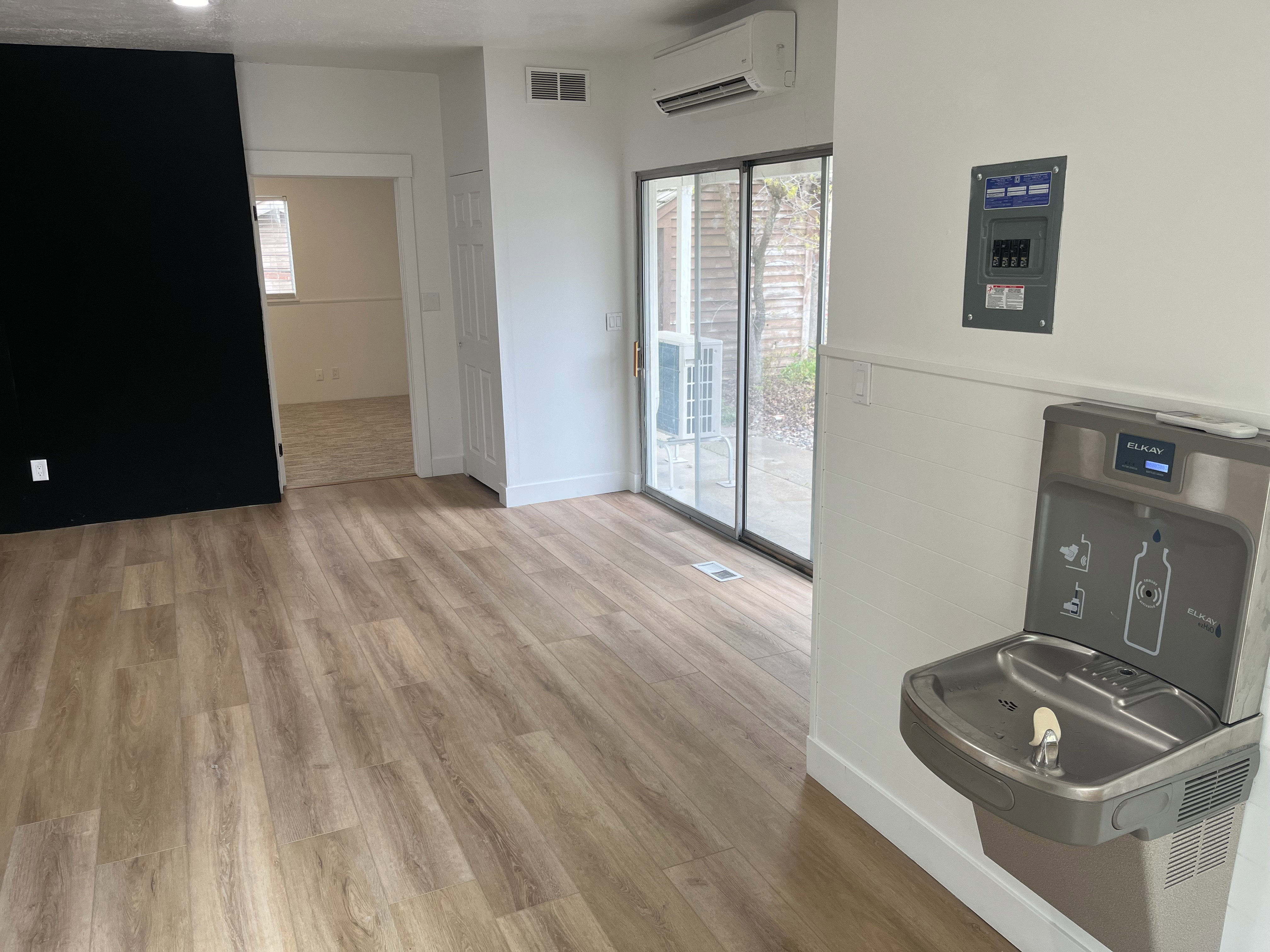 Open concept interior featuring wood-finish flooring, a contemporary black accent wall, and a built-in water fountain