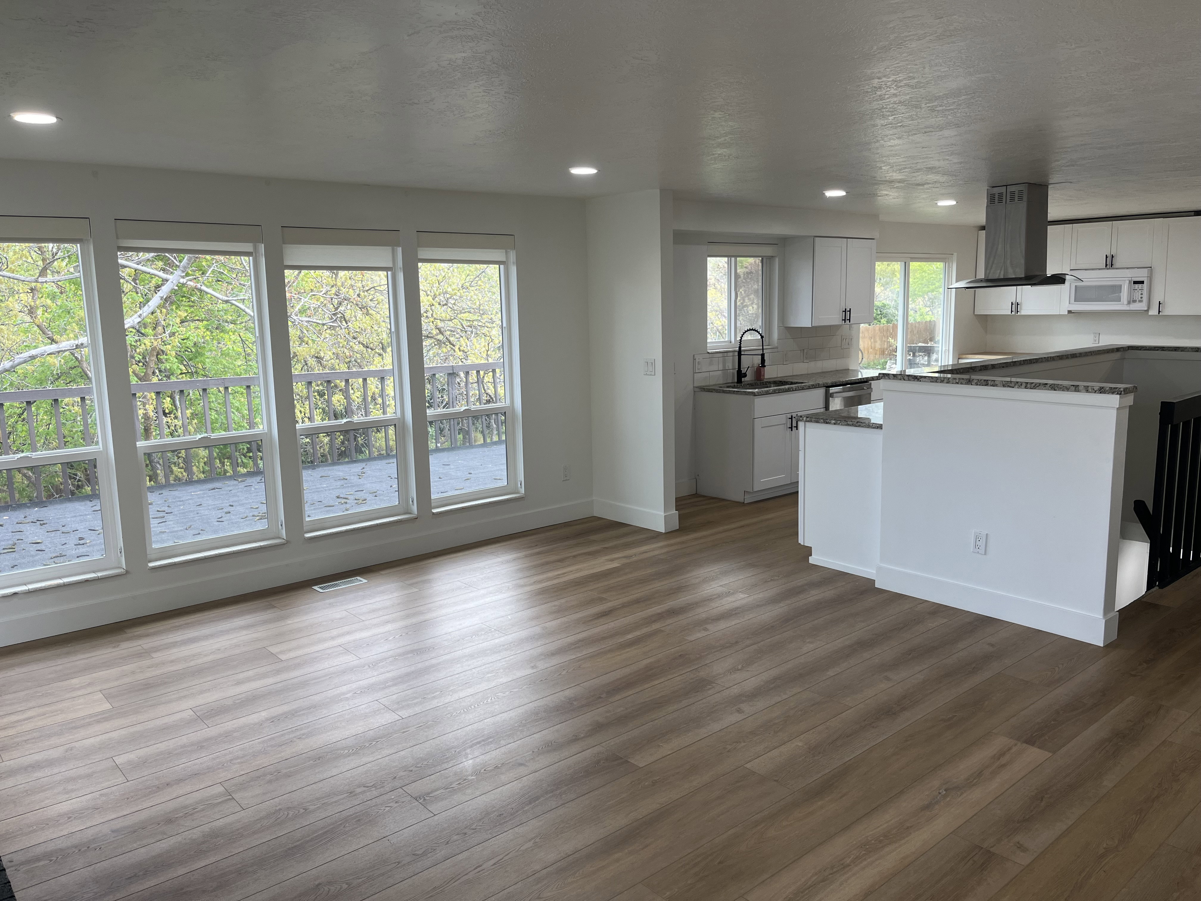Spacious room with wood-finish flooring, recessed lighting, and a wall of windows