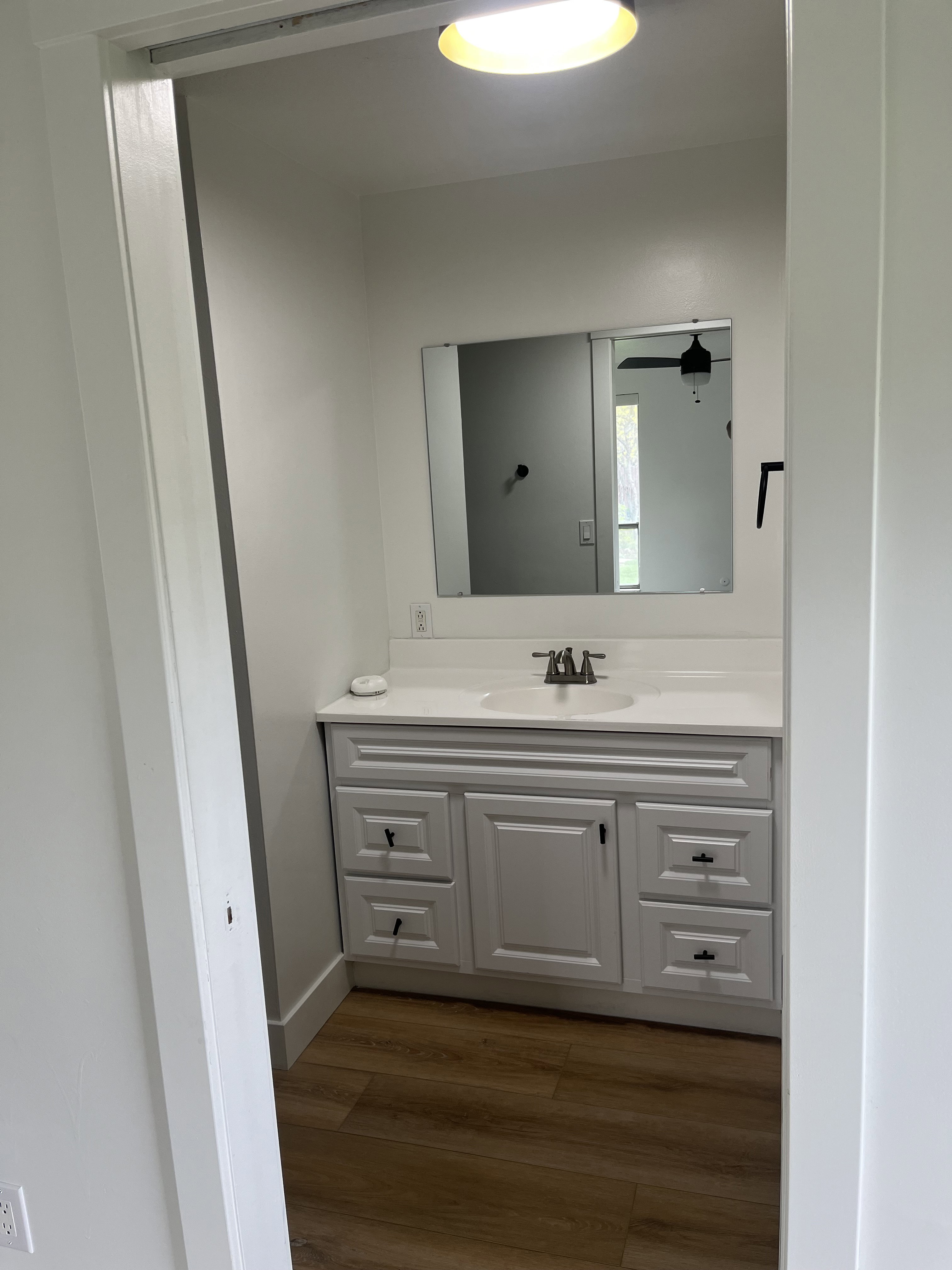 White vanity with a single sink, light countertop, and brushed nickel faucet