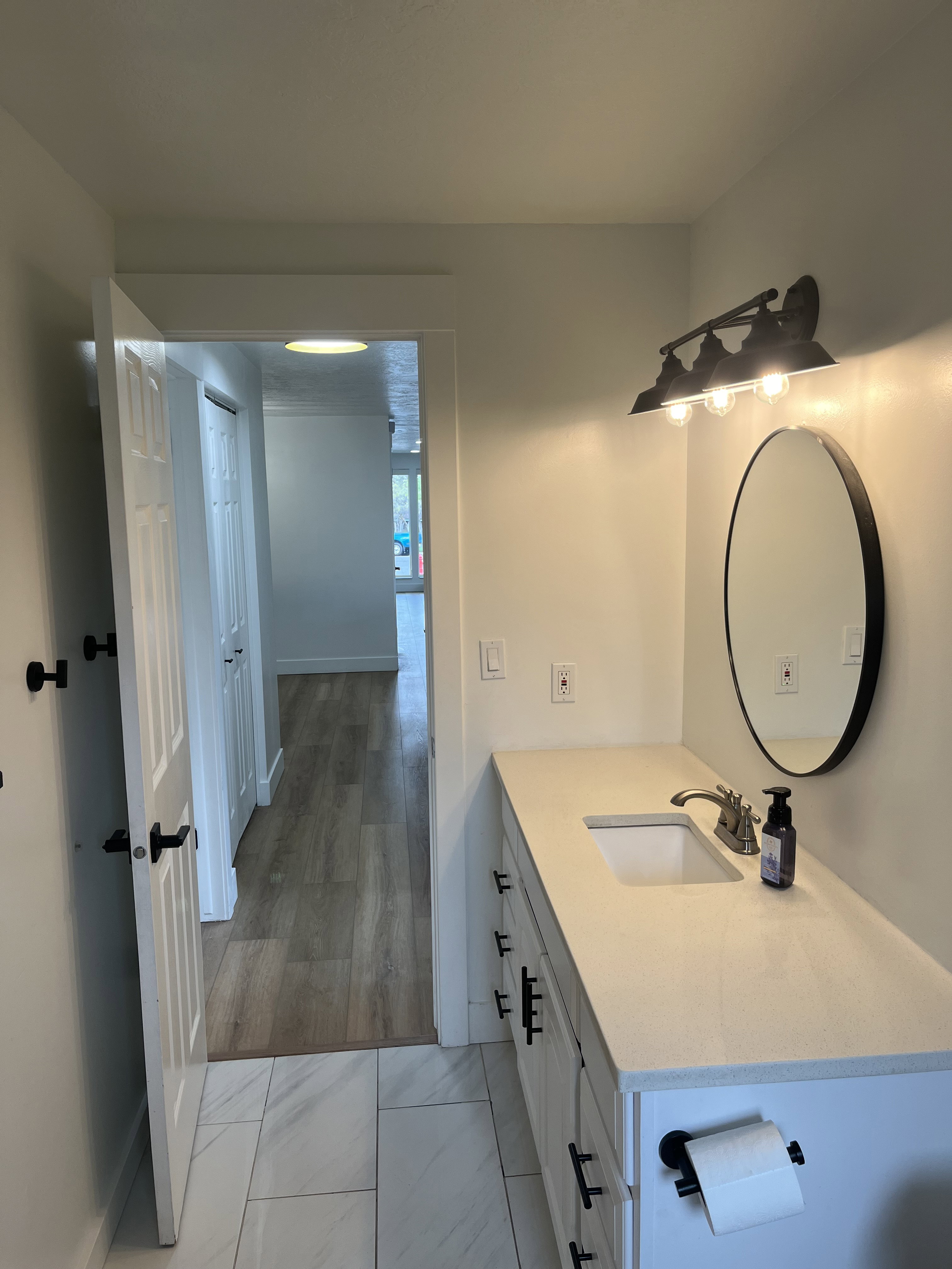 Bathroom vanity featuring a light-toned countertop with integrated sink, white cabinetry, and matte black hardware