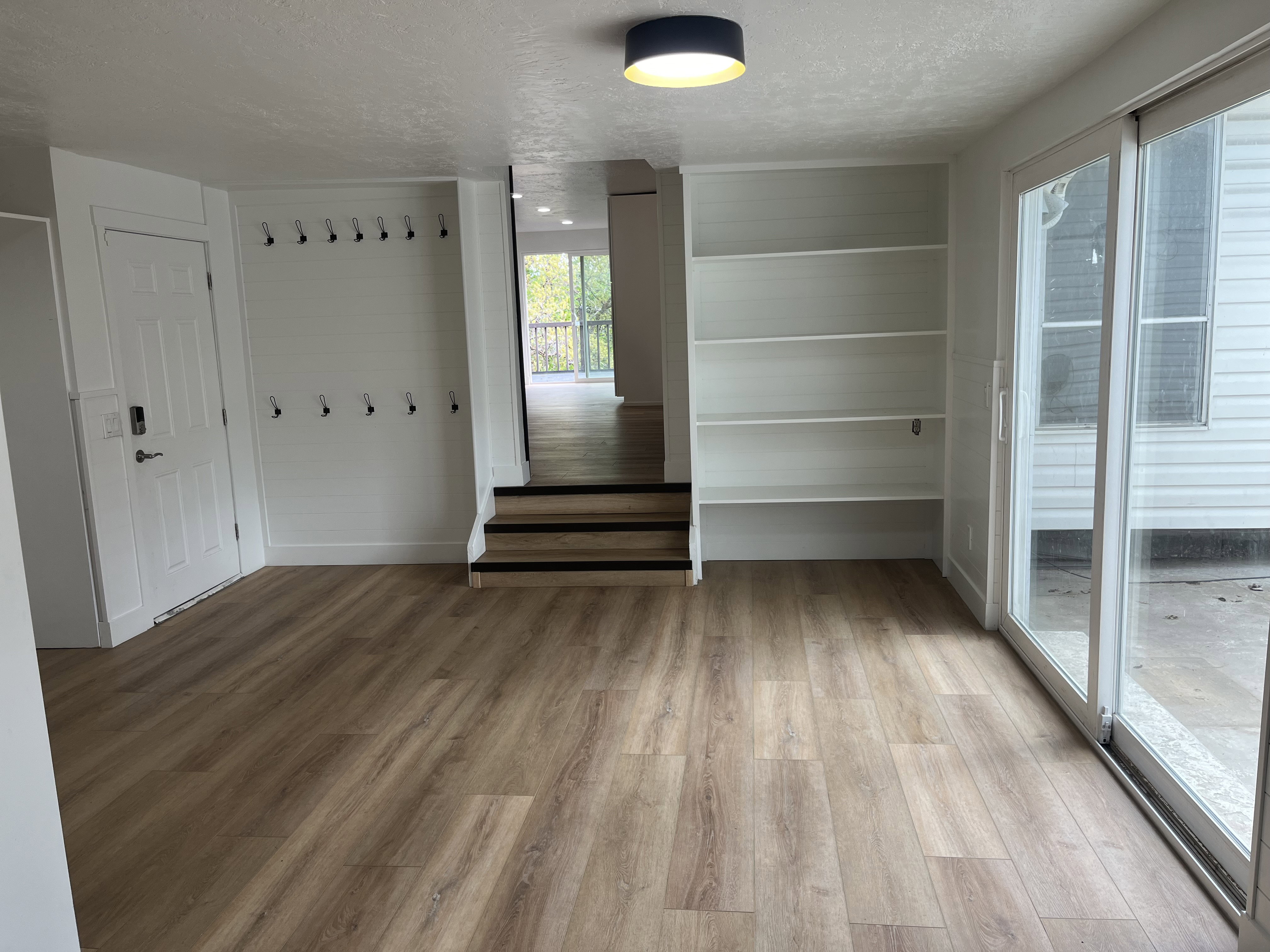Open-concept room featuring wood-finish flooring, built-in shelving, and a bright white sliding glass door