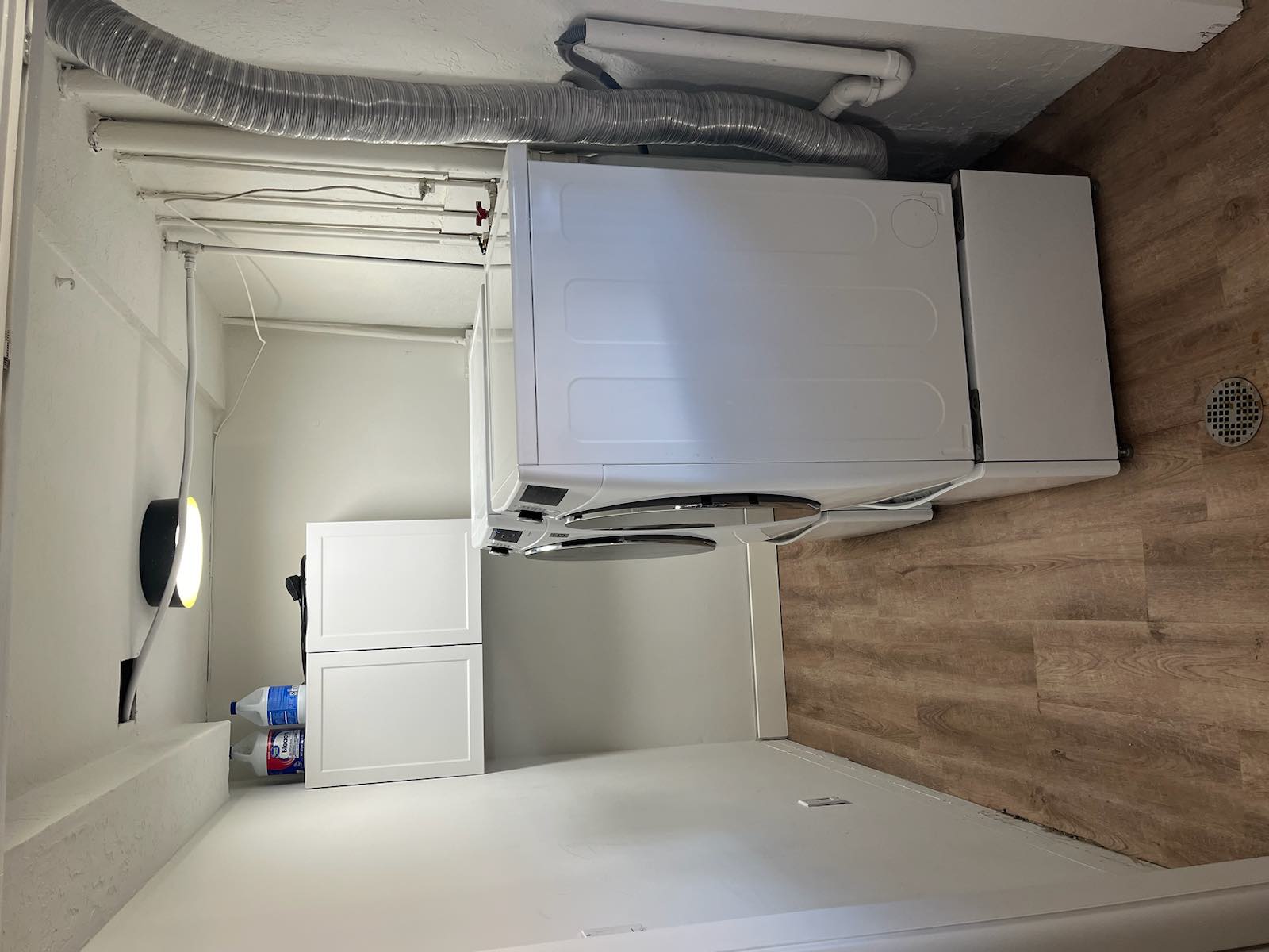 Dedicated laundry space featuring wood-finish flooring, white walls, and built-in white cabinetry for storage