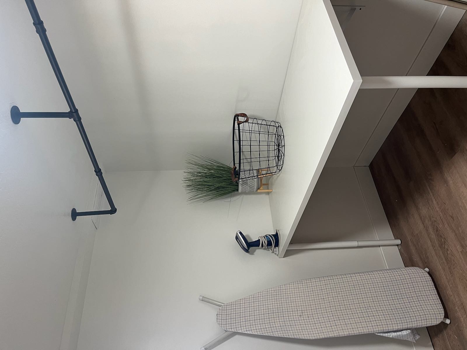 Functional utility space featuring a built-in white countertop, dark wood-finish flooring, and a ceiling-mounted black pipe hanging rack