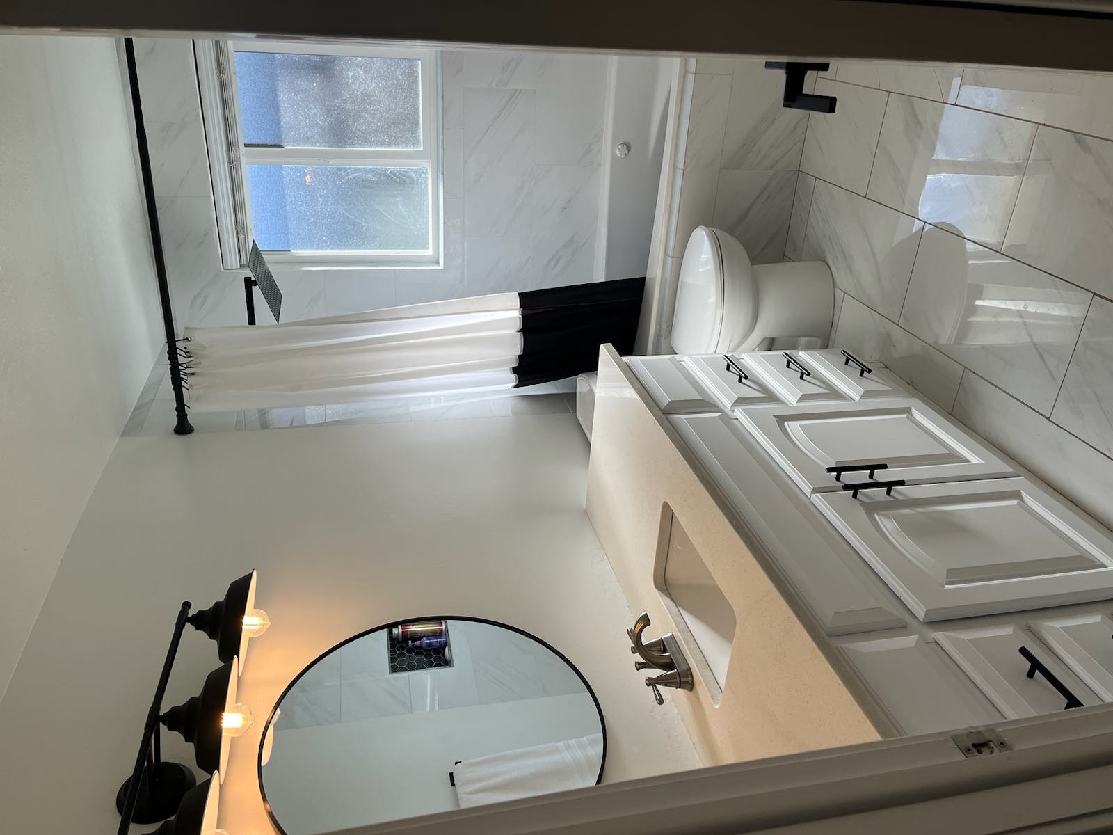 Bathroom featuring a white vanity with a light-toned countertop, rectangular undermount sink, and dark hardware