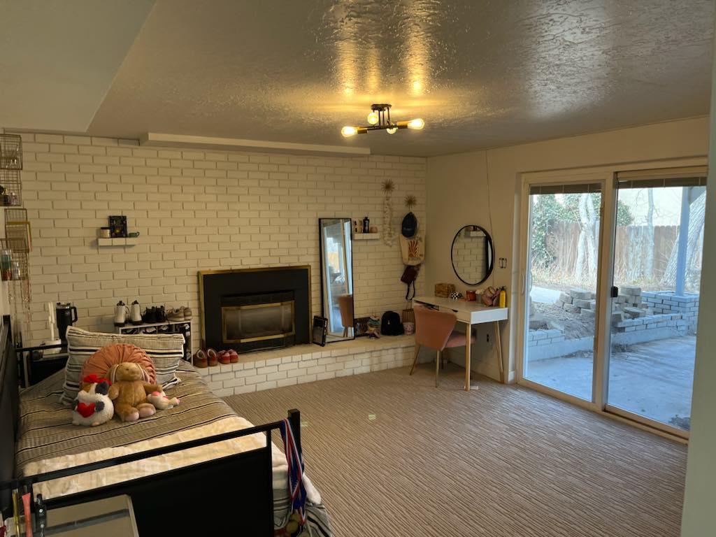 Room featuring a white brick fireplace with a black insert and hearth