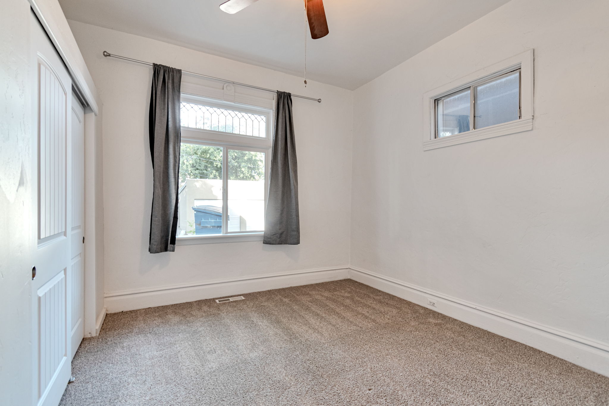 Carpeted room with white walls, baseboards, and ceiling fan