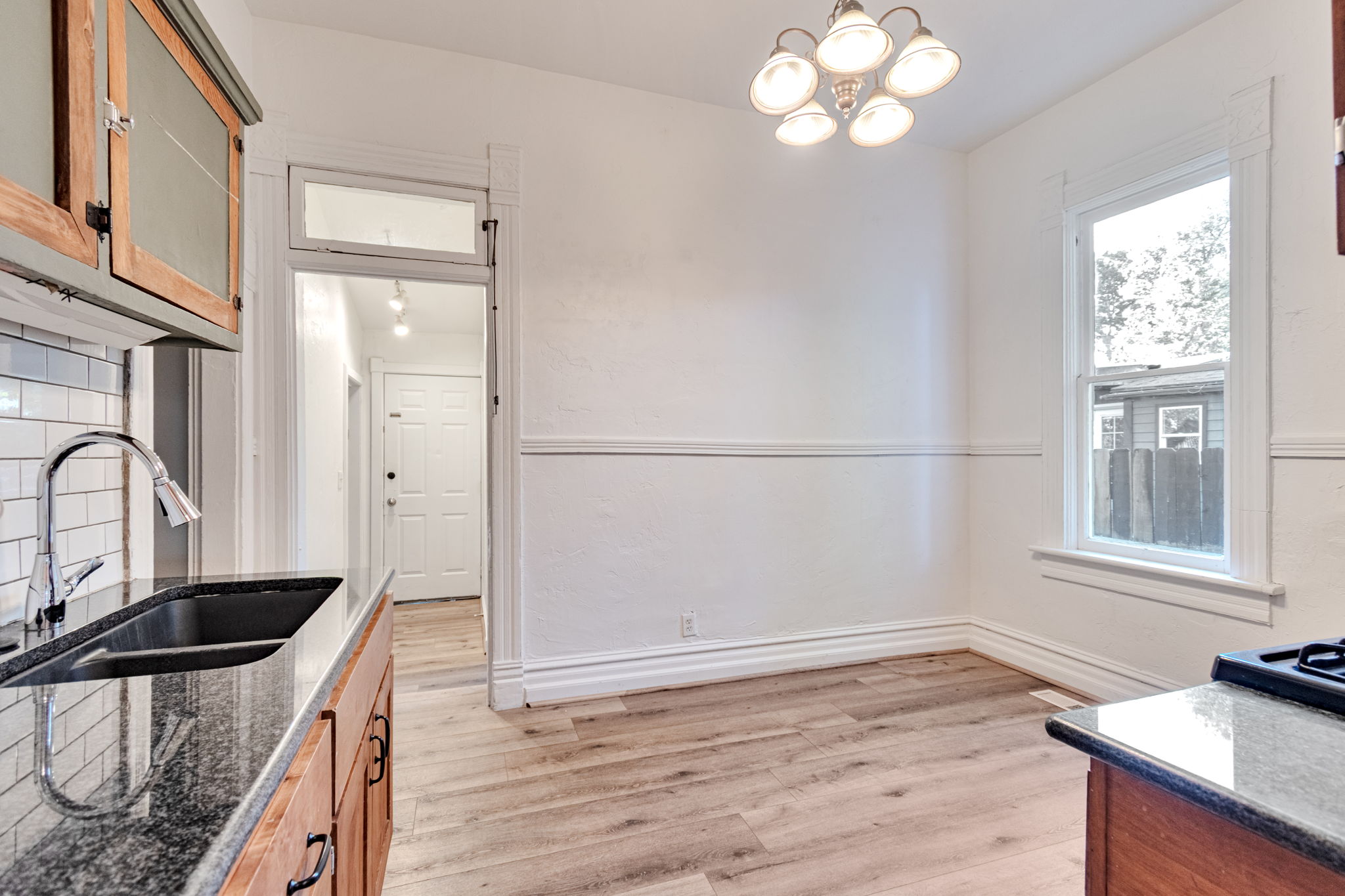 Kitchen and dining area featuring wood-finish flooring, white wainscoting, and a multi-light ceiling fixture