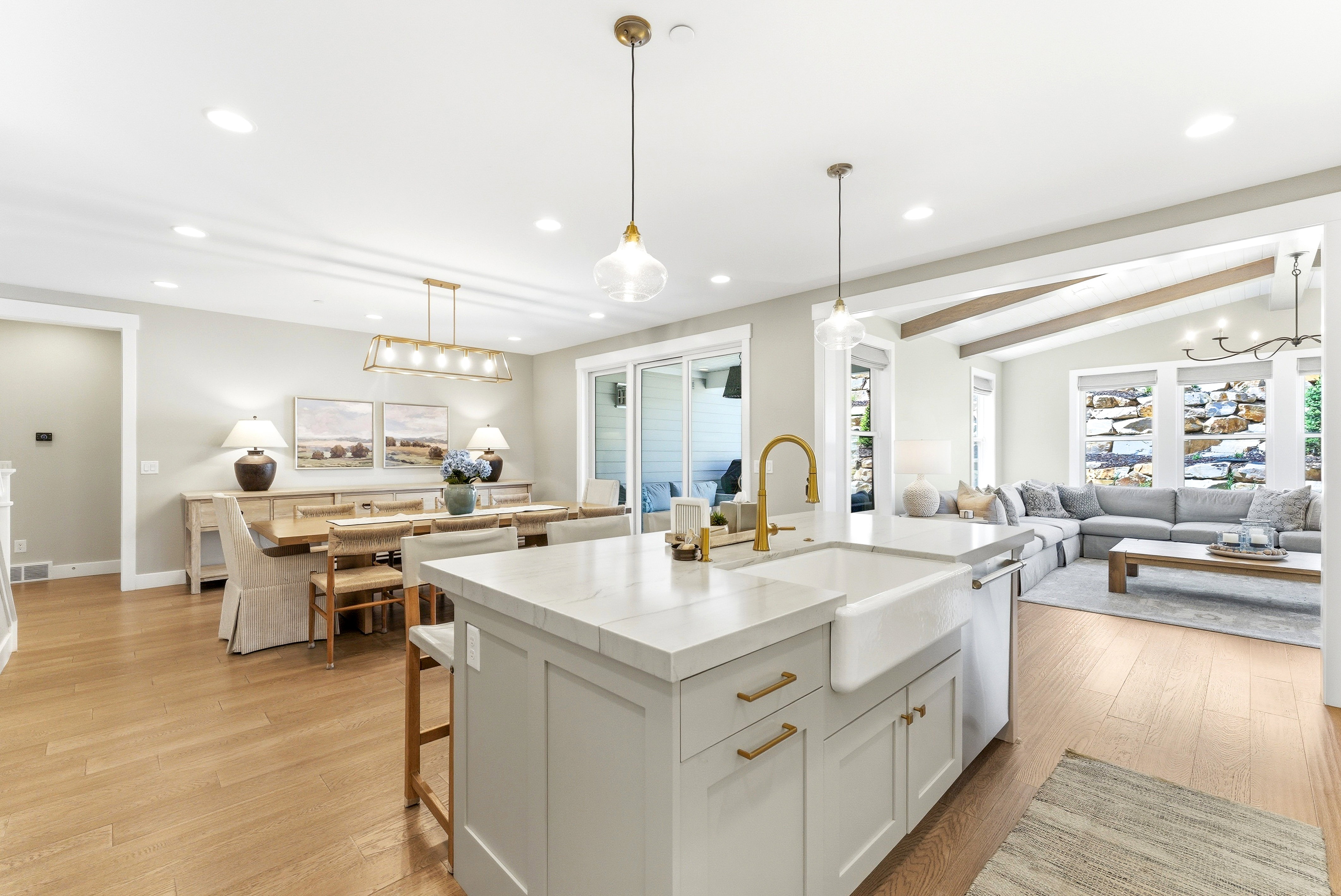 Kitchen island featuring a farmhouse sink and brass-finish faucet, complemented by wood-finish flooring