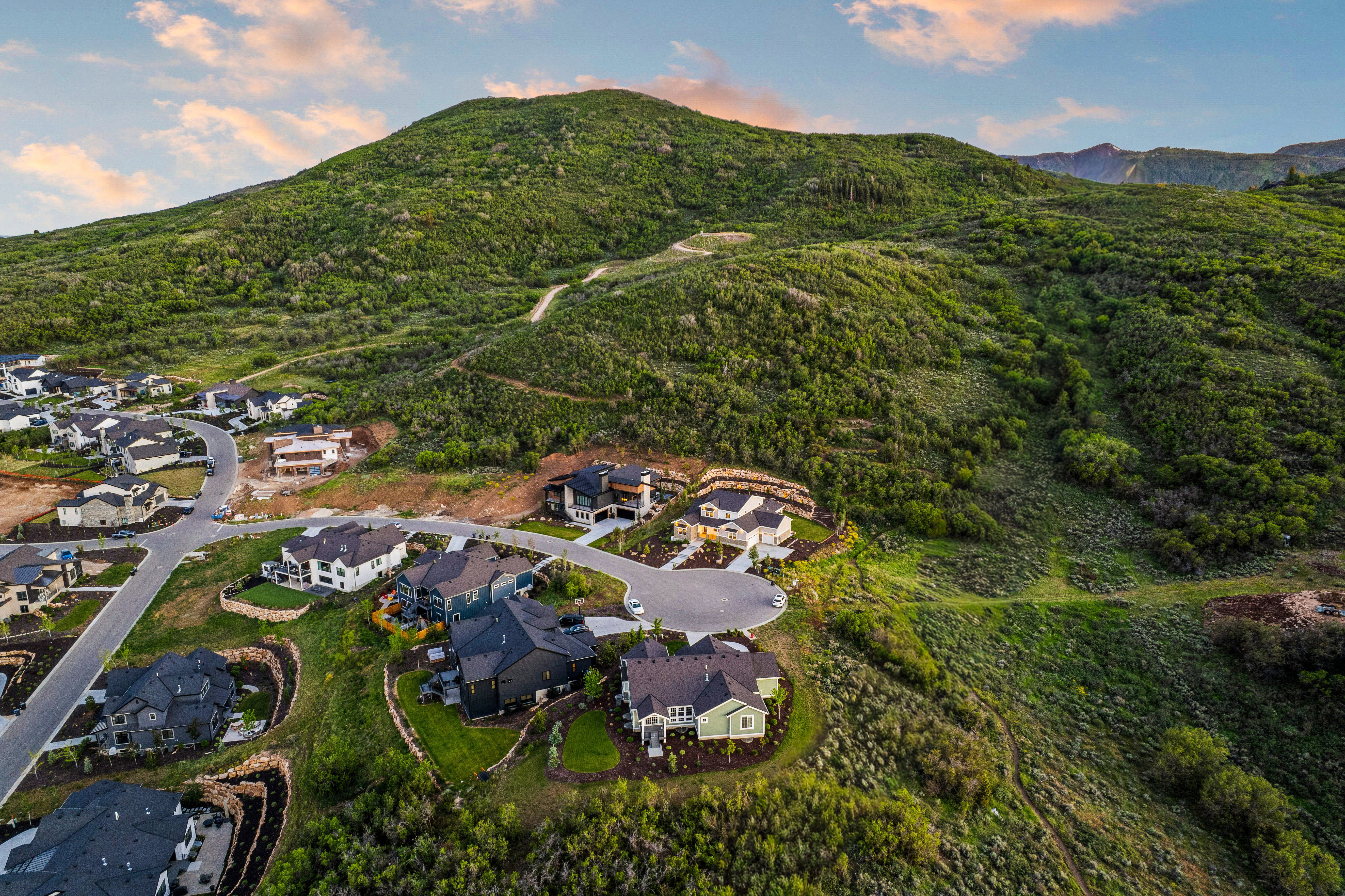 Residential development situated at the base of a verdant, tree-covered mountain