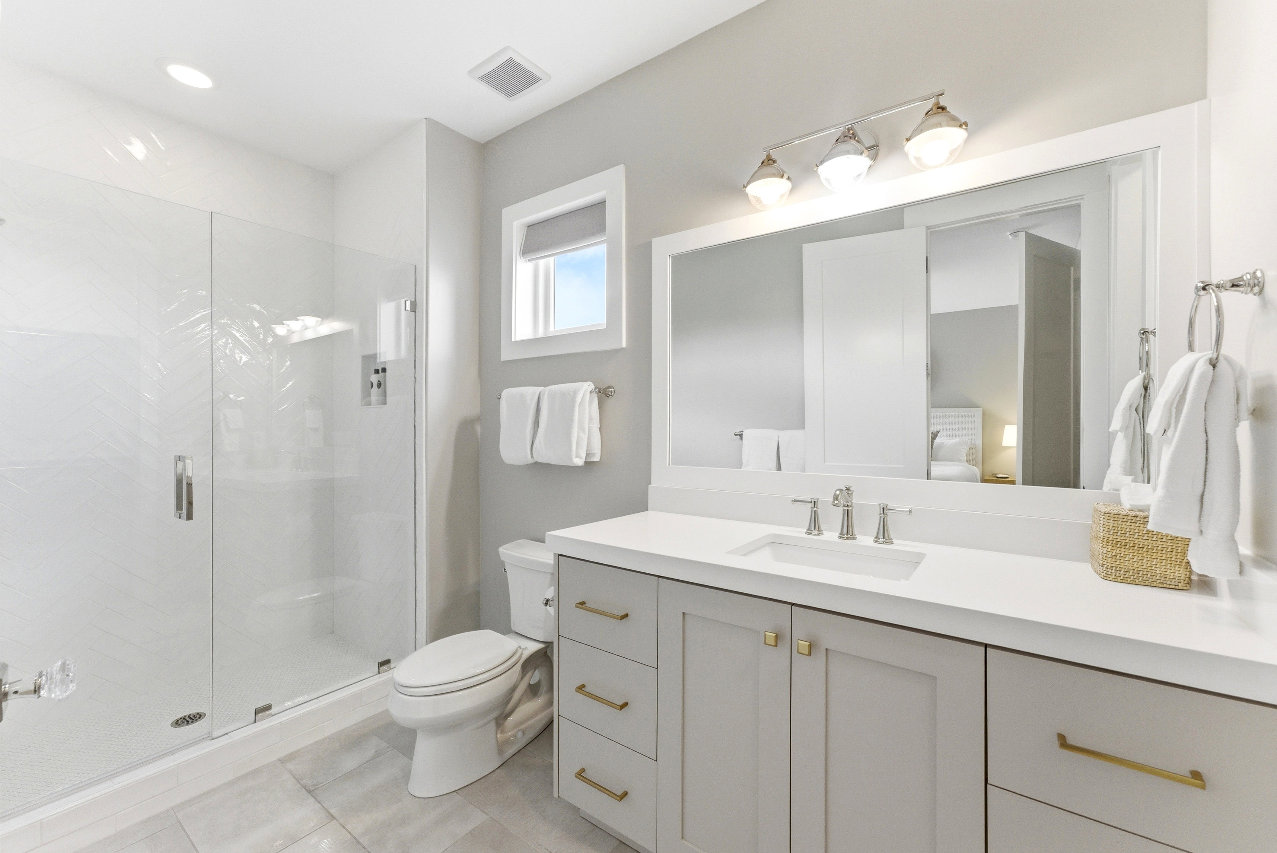 Bathroom featuring a glass-enclosed shower, single-basin vanity with light gray cabinetry, white countertop, and a vanity mirror with overhead lighting