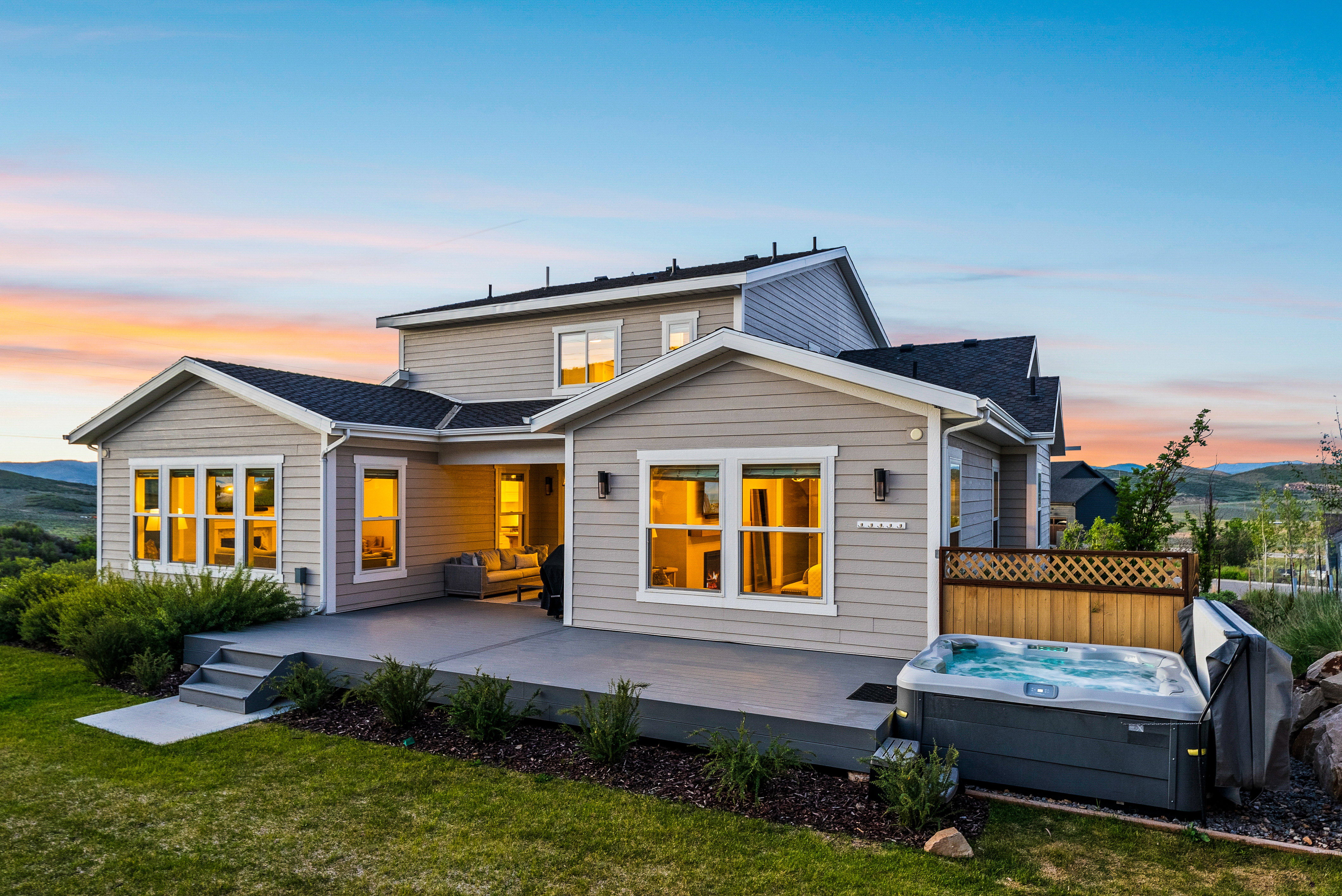 Rear elevation featuring a multi-level concrete patio, integrated hot tub, and a covered outdoor living area