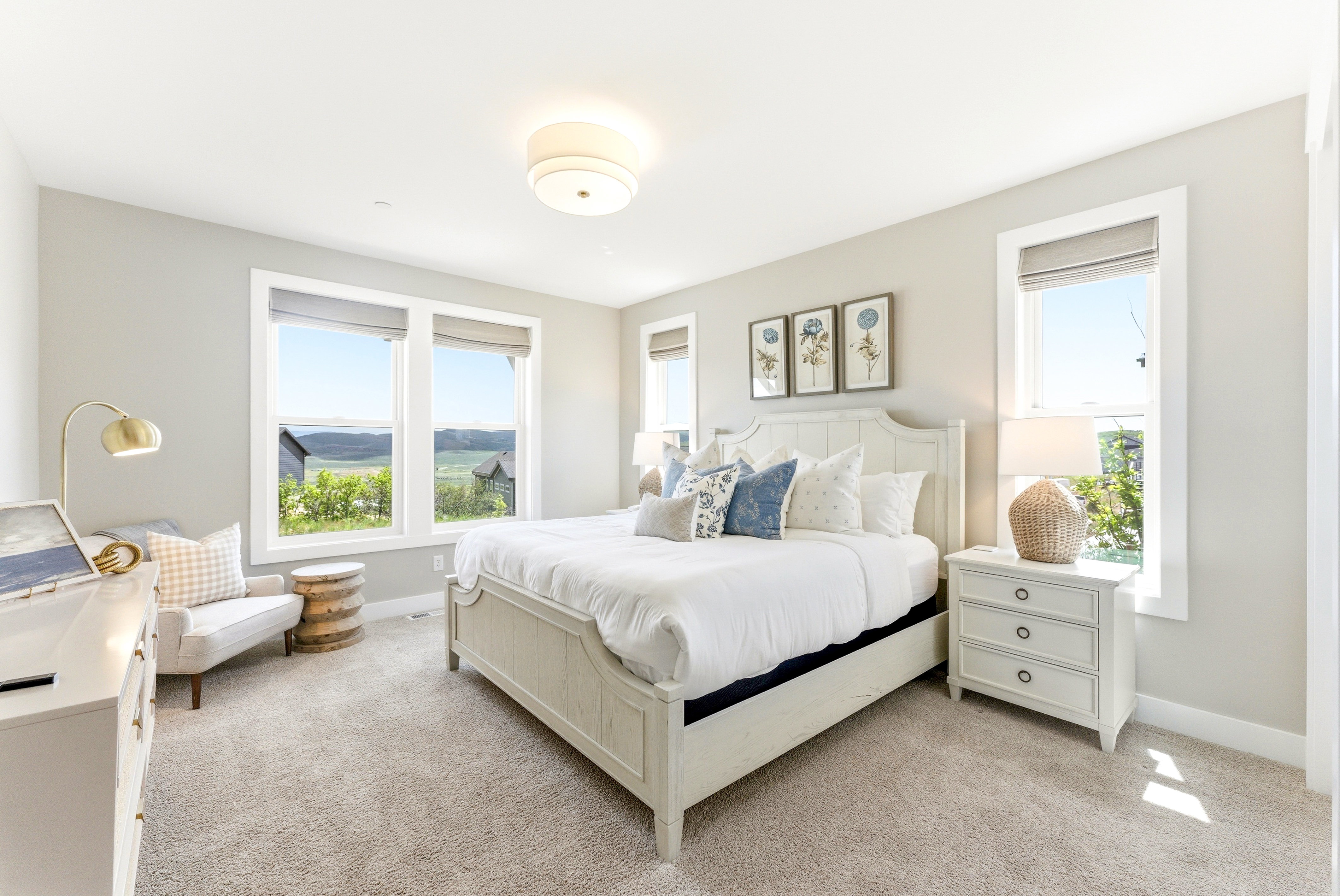 Spacious room featuring multiple windows with natural scenery, light neutral wall paint, and soft carpeting