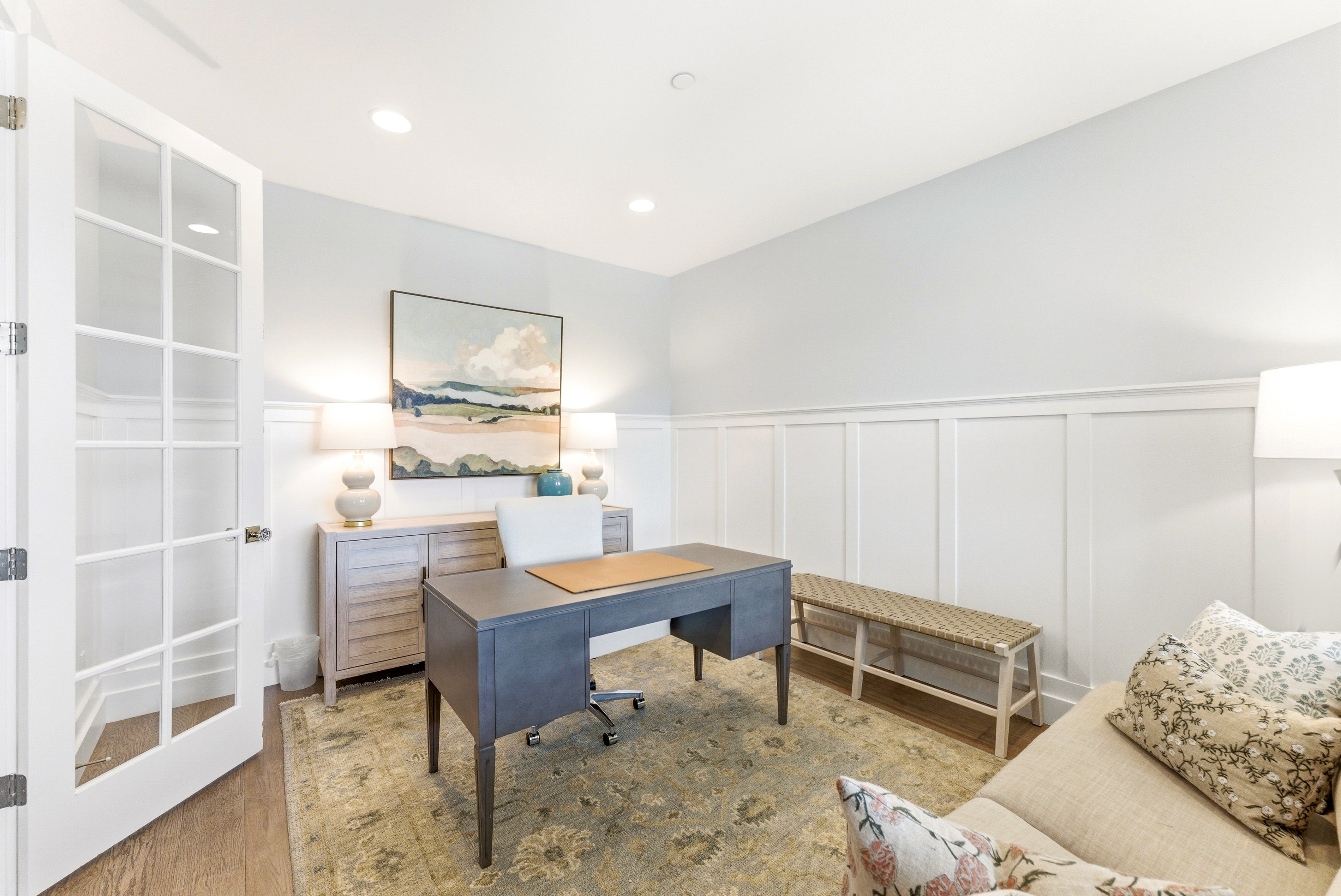 French doors with glass lites, wood-finish flooring, recessed ceiling lighting, and wainscoting details characterize this interior space