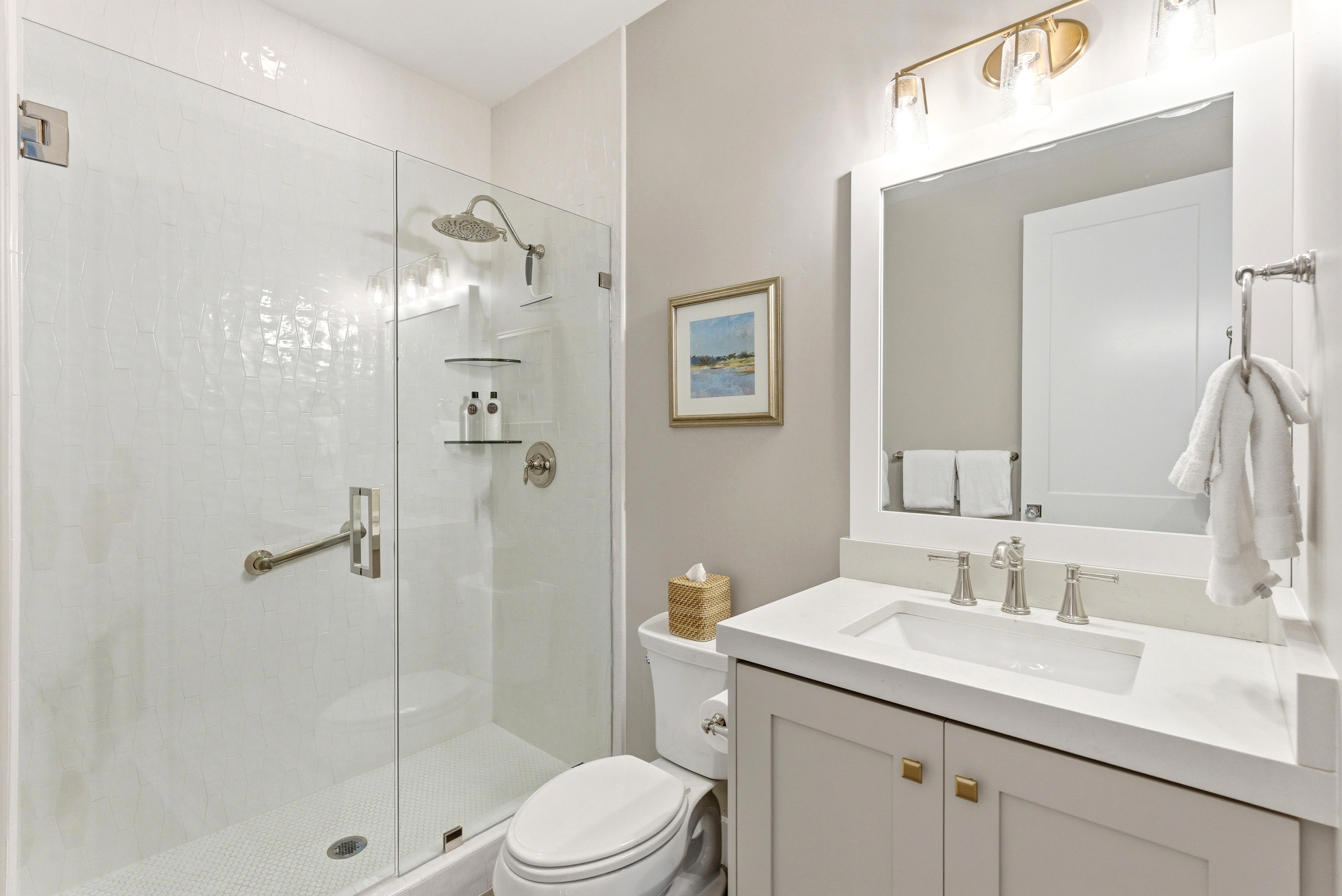 Contemporary bathroom featuring a frameless glass shower enclosure with white textured tile surround and a rain showerhead