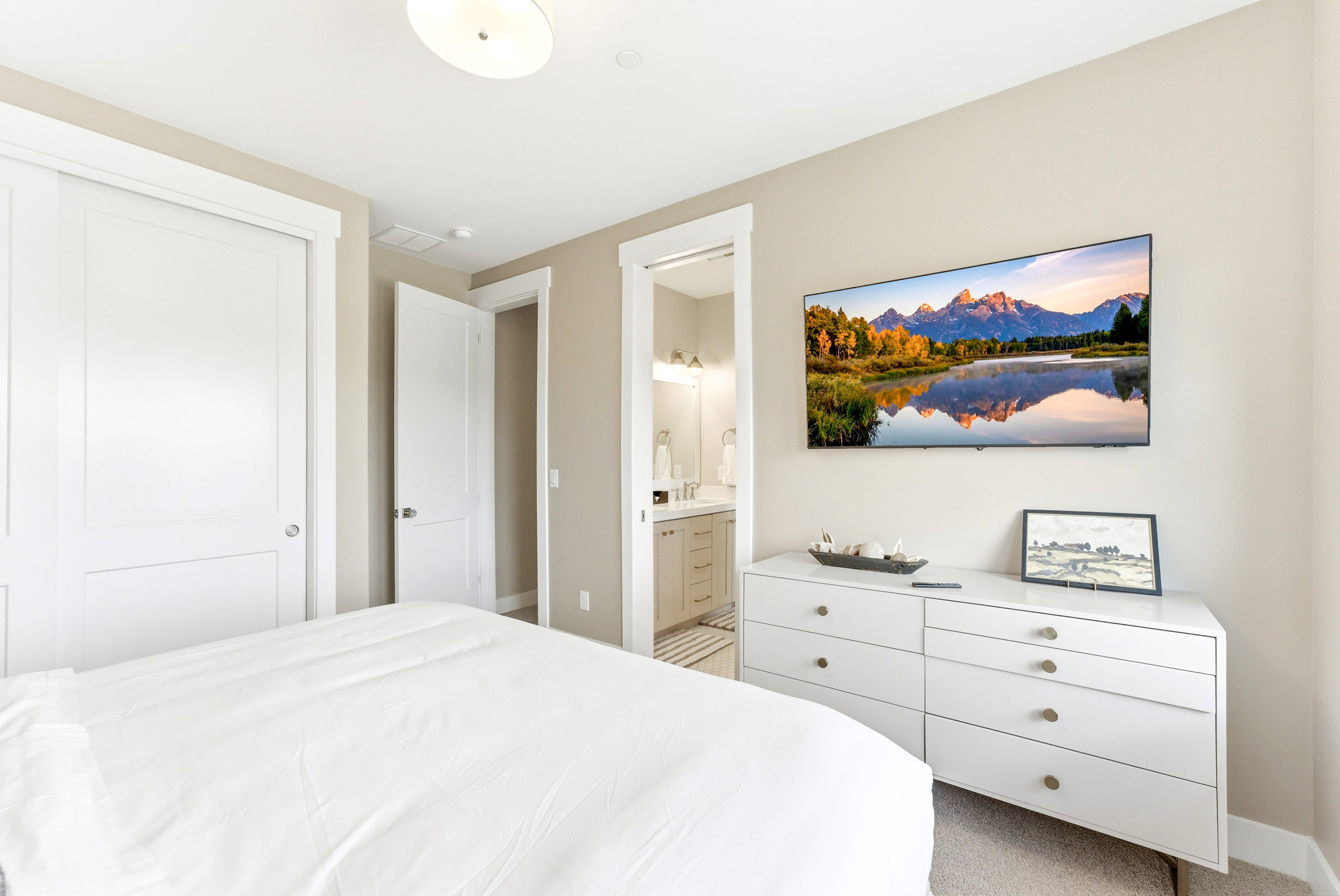 Recessed lighting illuminates a space featuring light neutral walls and light-toned carpet