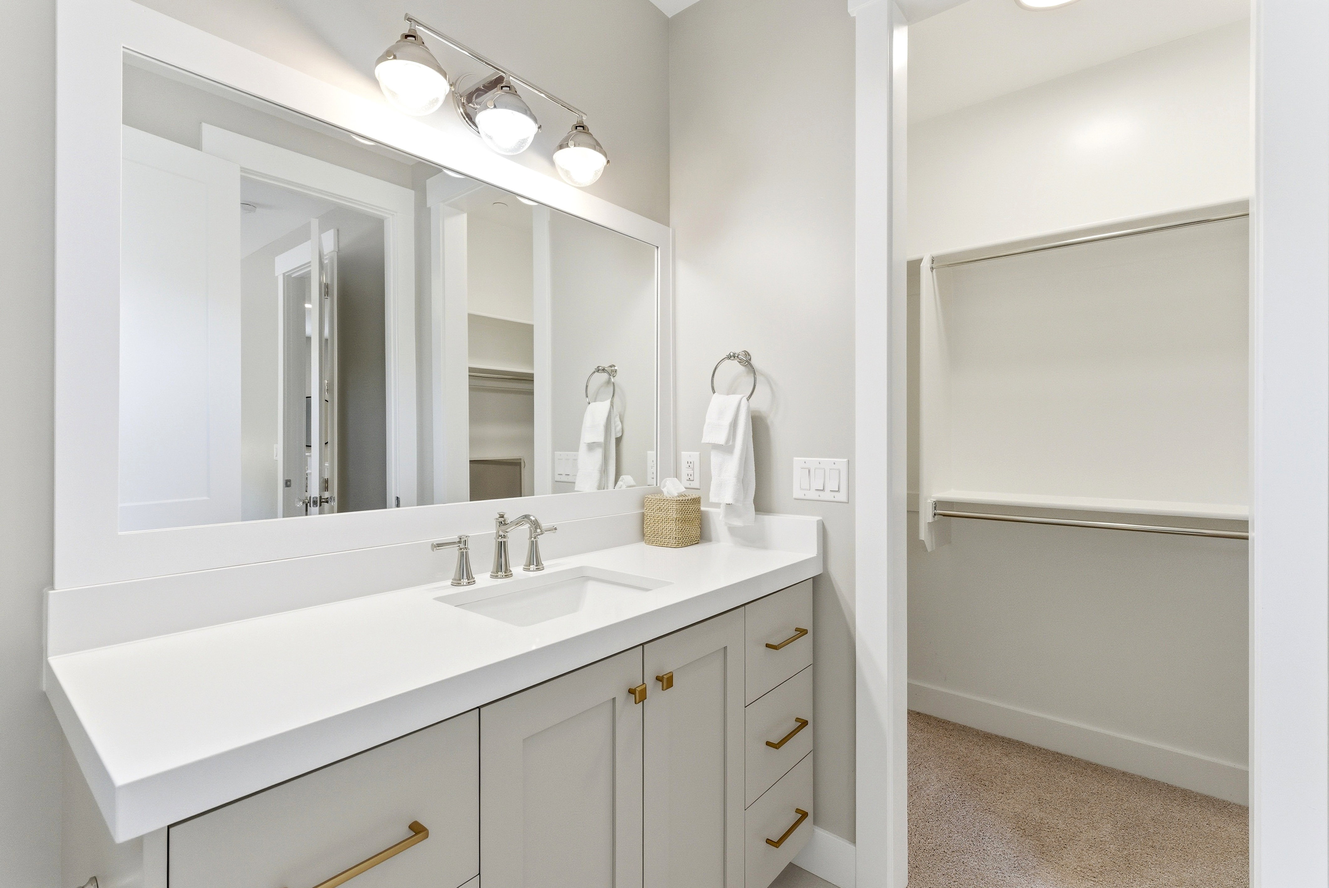 Bathroom vanity featuring a single basin sink, brushed nickel faucet, and a large framed mirror with integrated lighting