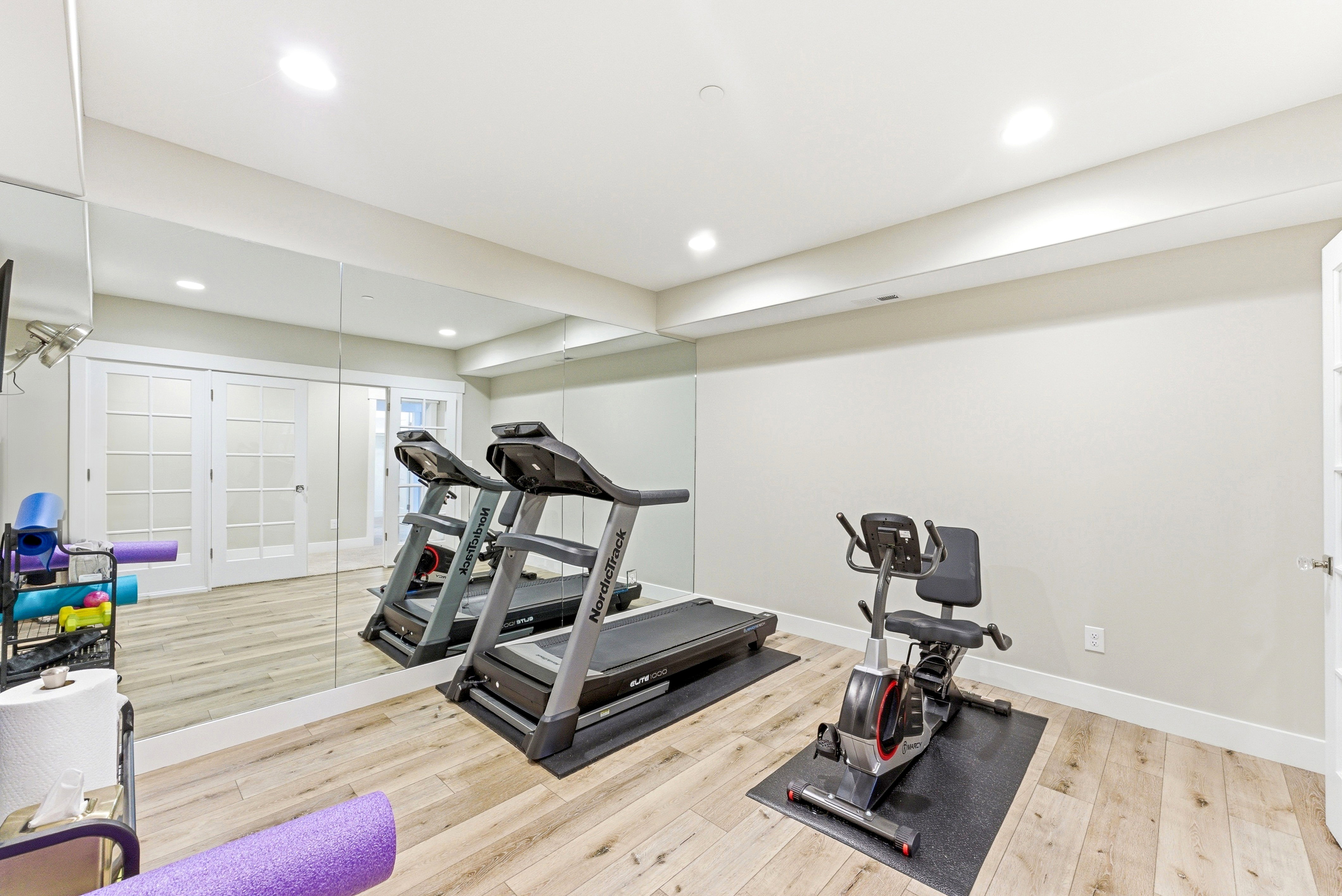Spacious room featuring light wood-finish flooring and a full wall of mirrored panels