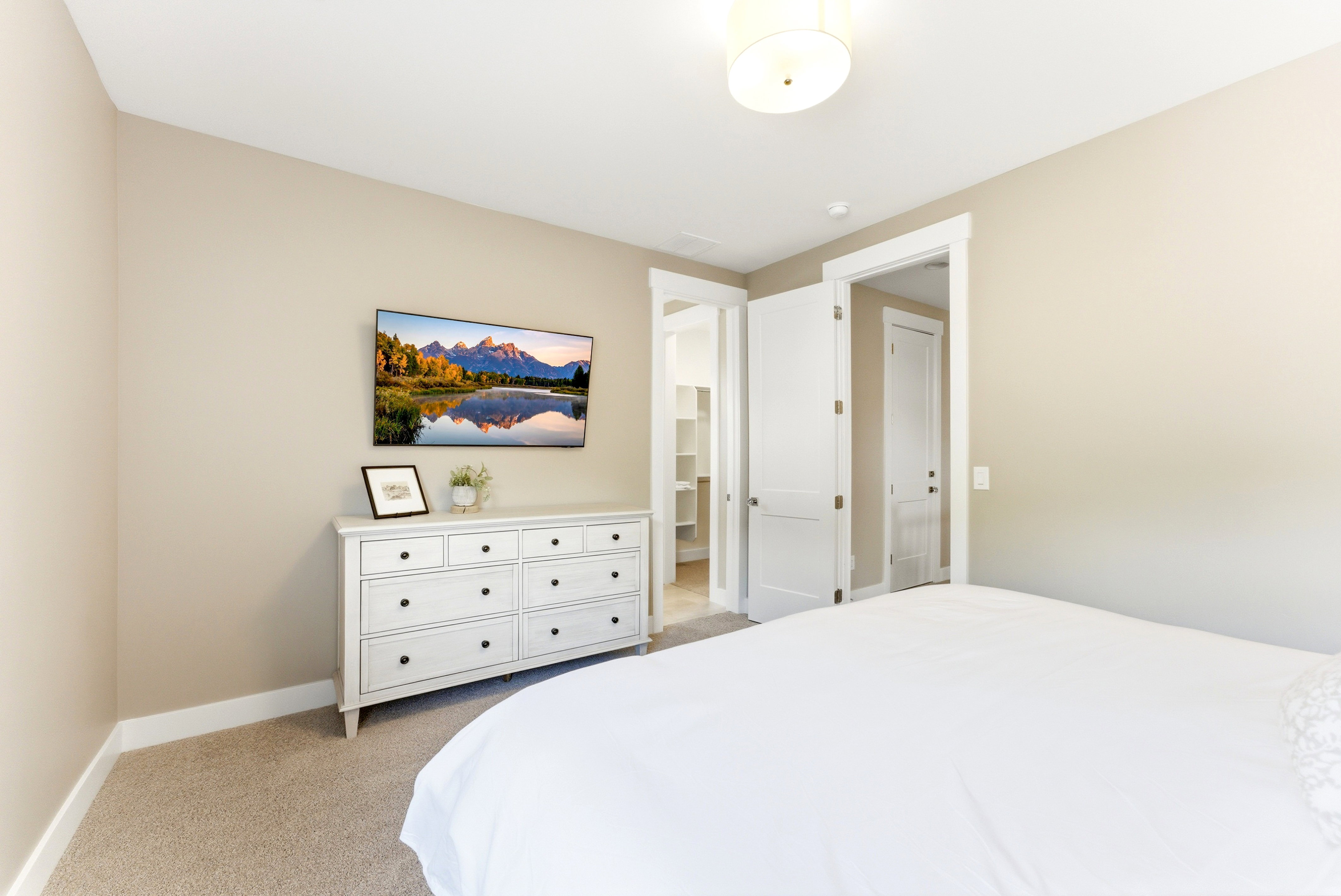 Carpeted bedroom featuring neutral-toned walls, white trim, and a flush-mount ceiling light