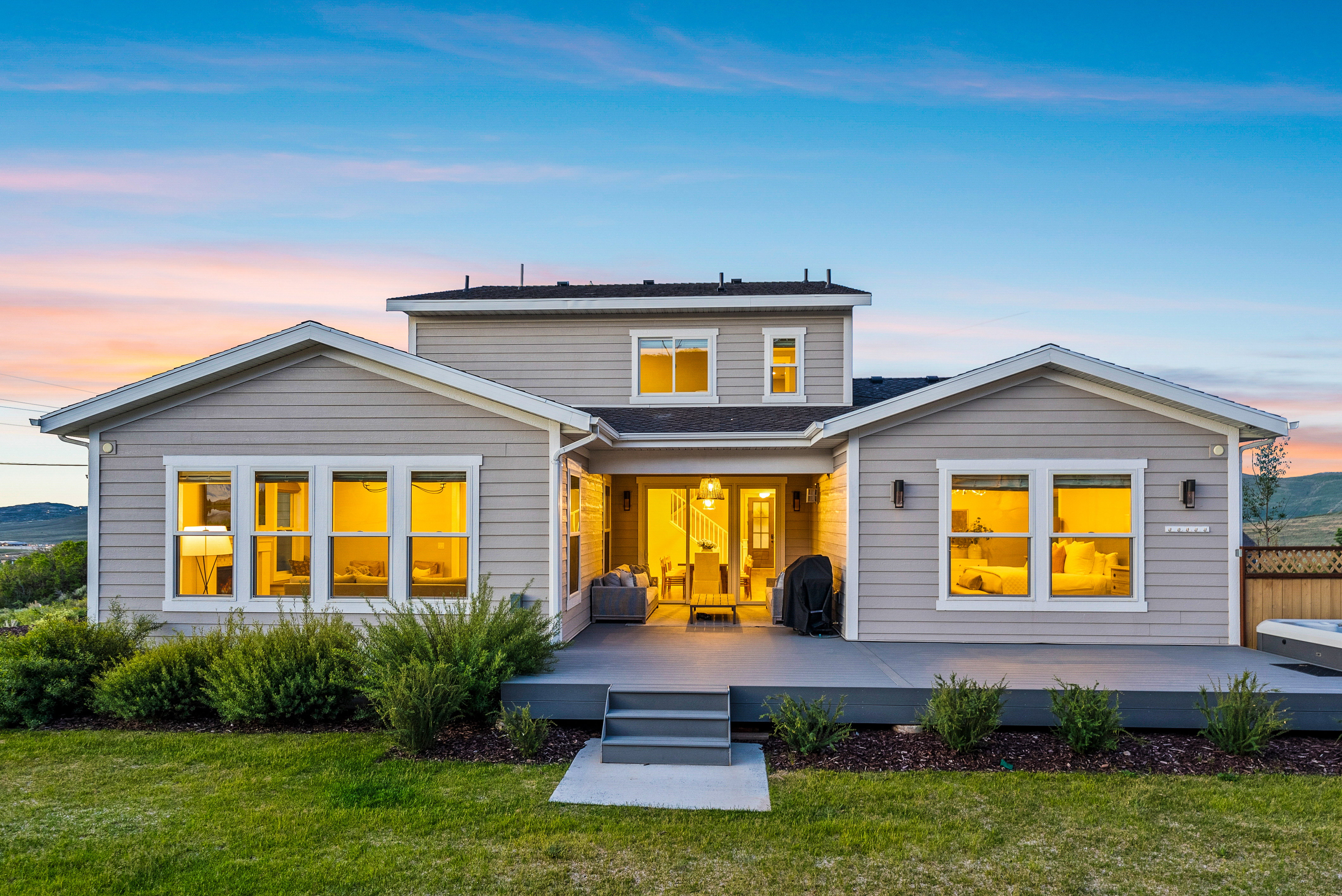 Rear exterior featuring a multi-level composite deck, expansive lawn, and horizontal siding