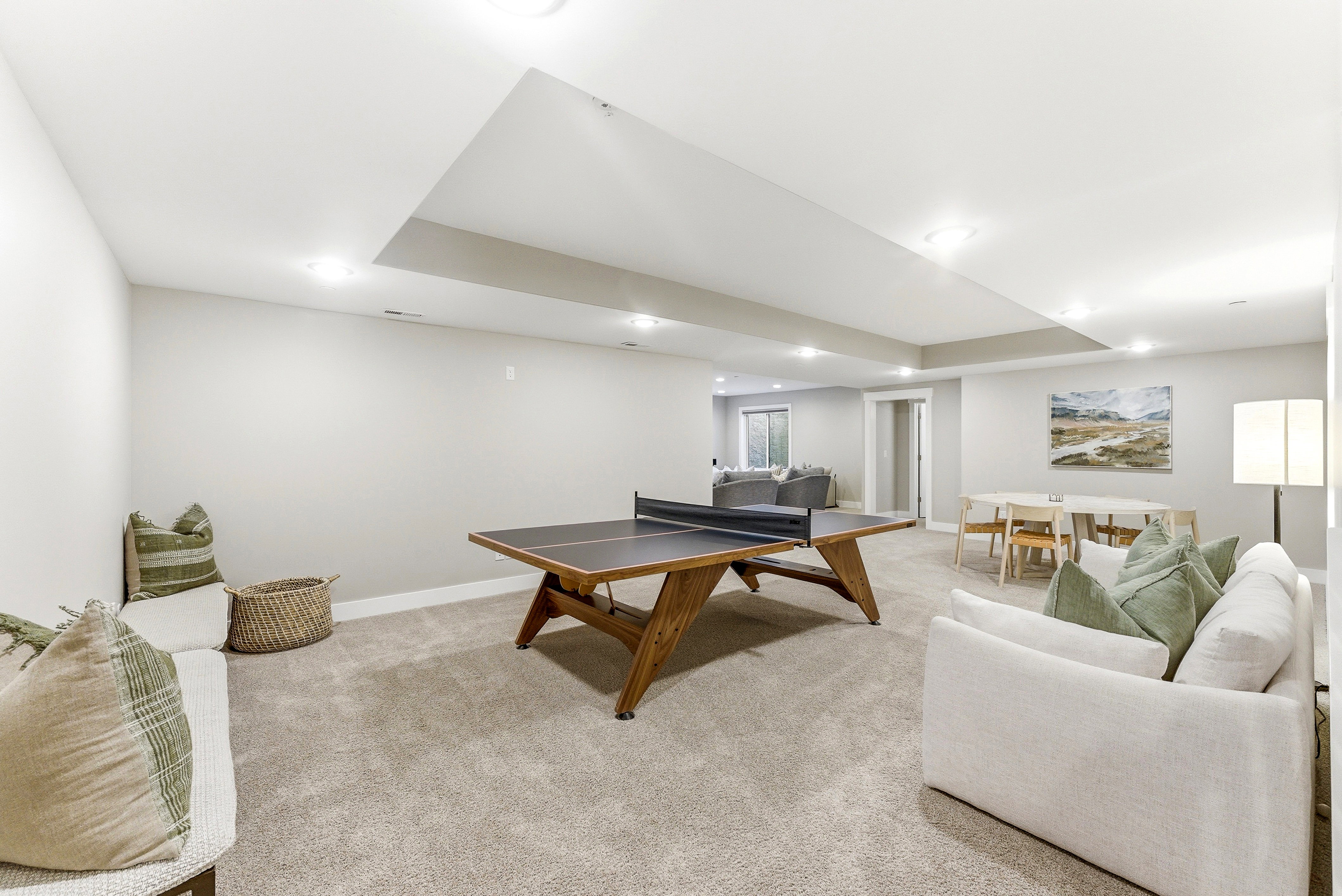 Spacious finished room featuring neutral carpet flooring, recessed lighting, and a tray ceiling detail