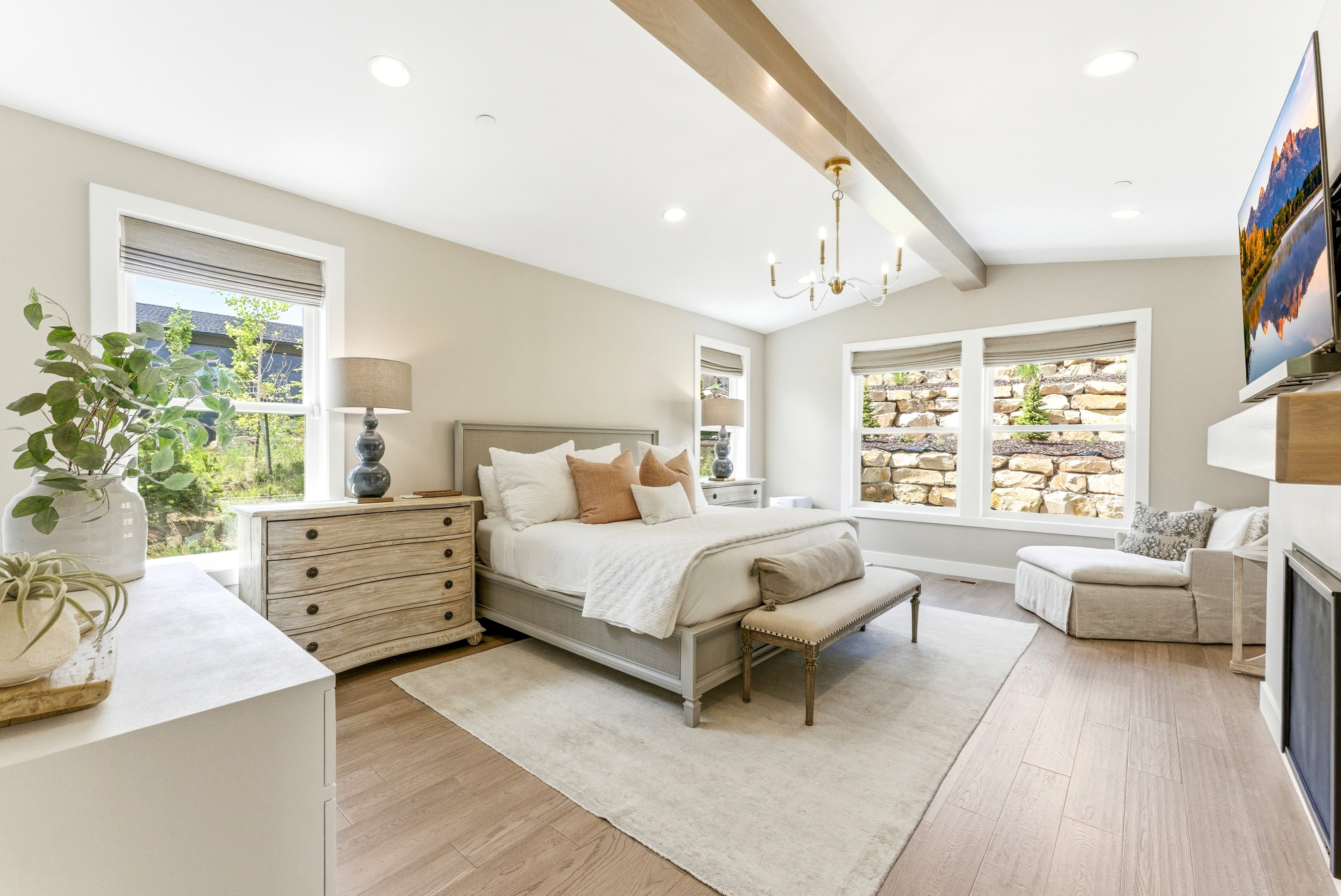Spacious room featuring vaulted ceilings with exposed wood beams, a modern chandelier, and recessed lighting