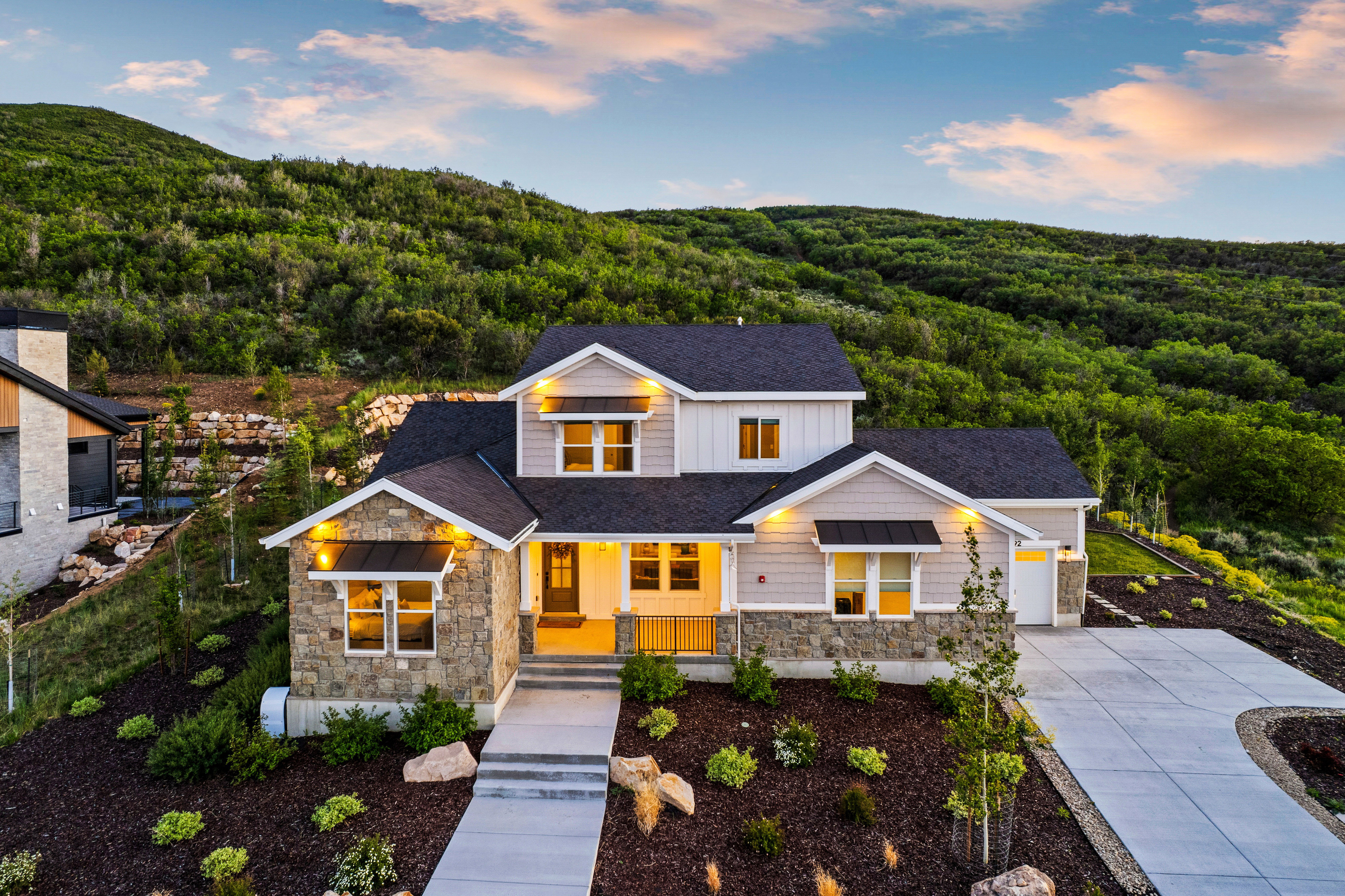 Contemporary residence featuring a stone and siding exterior, a dark shingle roof, and a concrete driveway