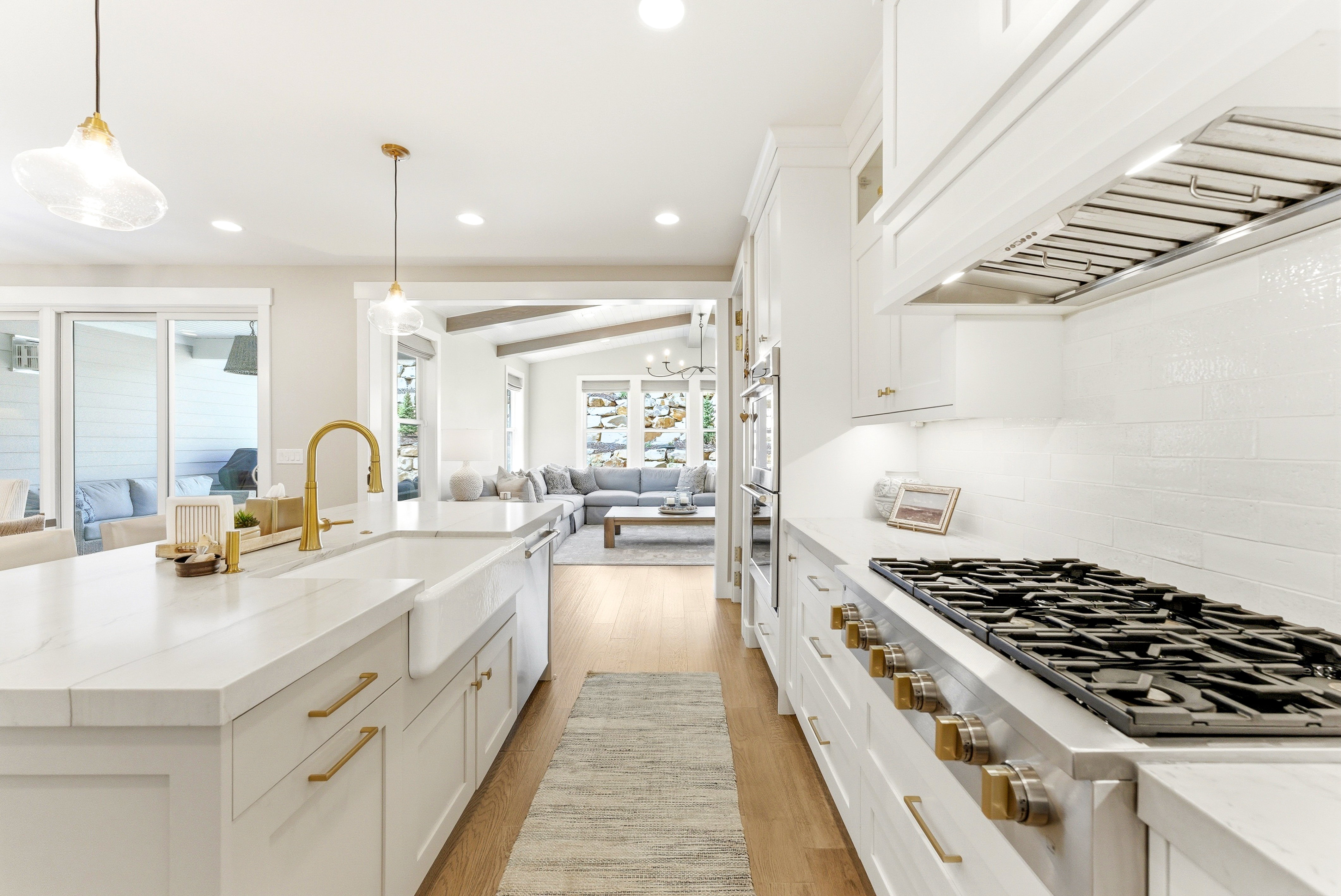 Gourmet kitchen featuring a large island with a farmhouse sink, brass-finish faucet, and pendant lighting