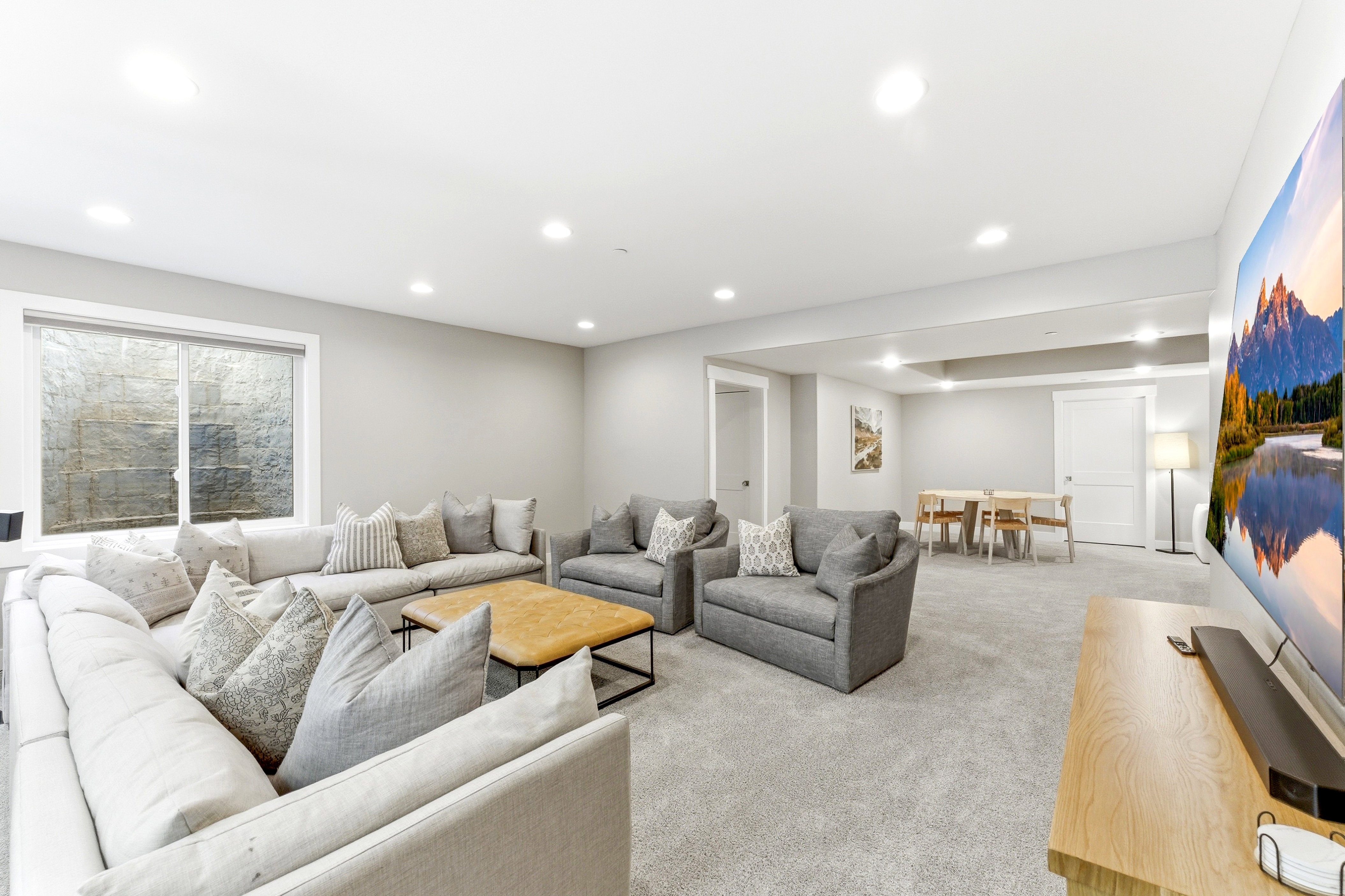 Spacious lower-level living area with recessed lighting and neutral carpet flooring