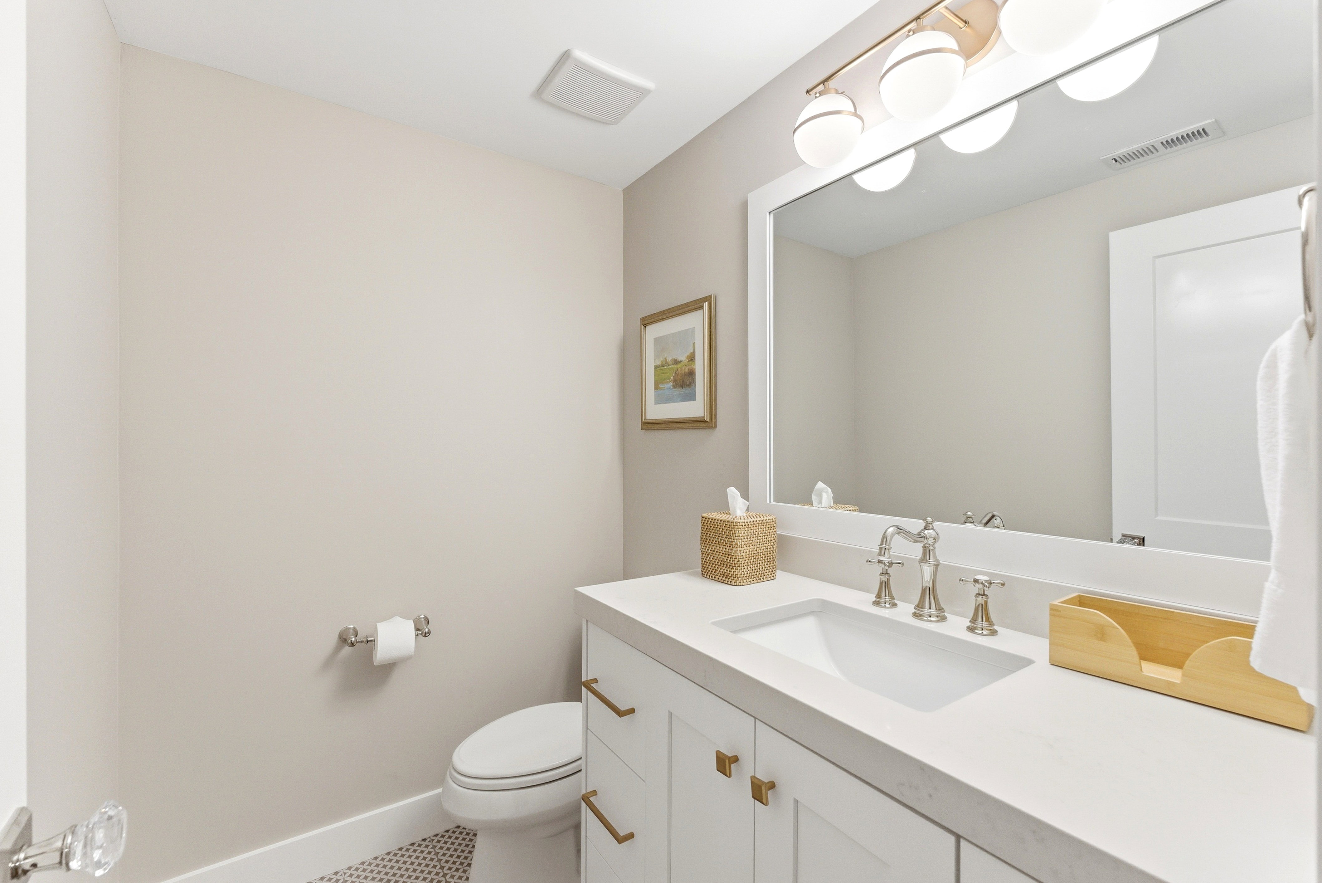Contemporary bathroom featuring a white vanity with gold-finish hardware, a large mirror, and an integrated sink with a polished nickel faucet
