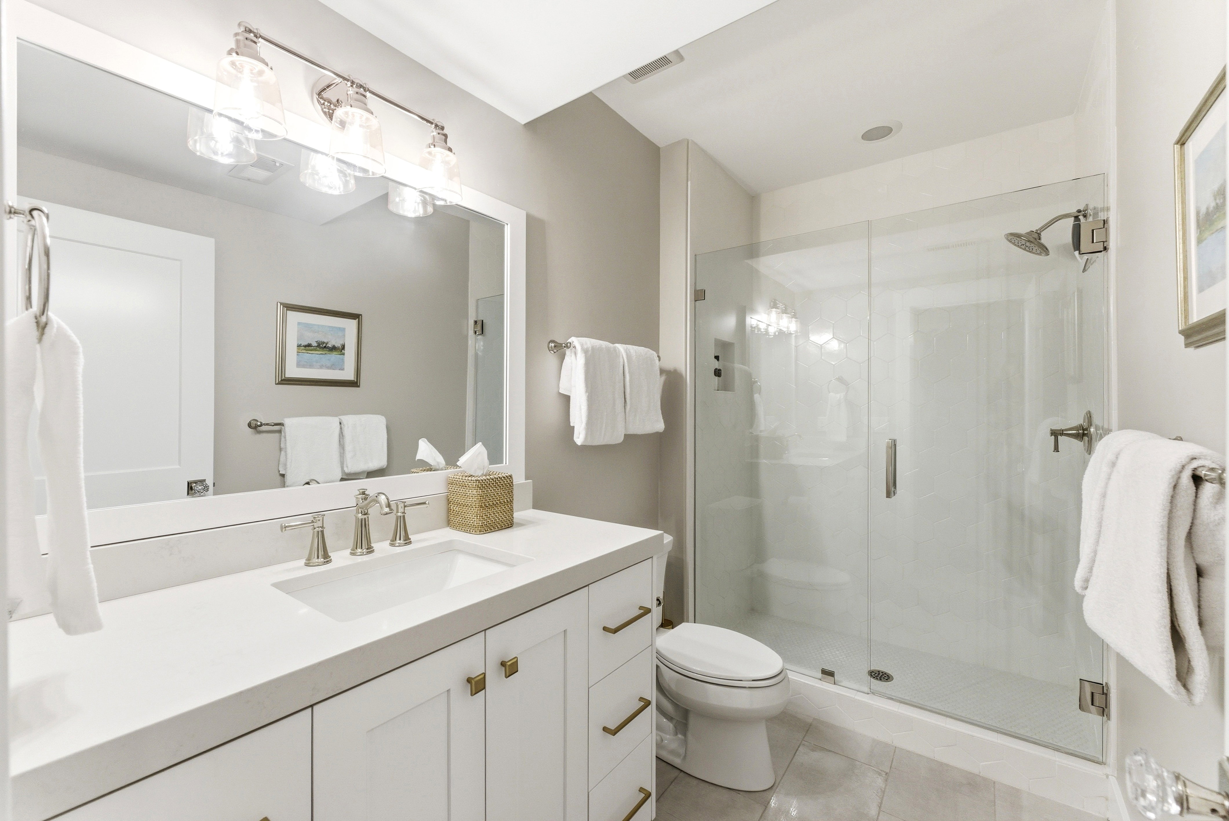 Modern bathroom featuring a frameless glass shower enclosure, a vanity with white cabinetry, brushed nickel hardware, and a single basin