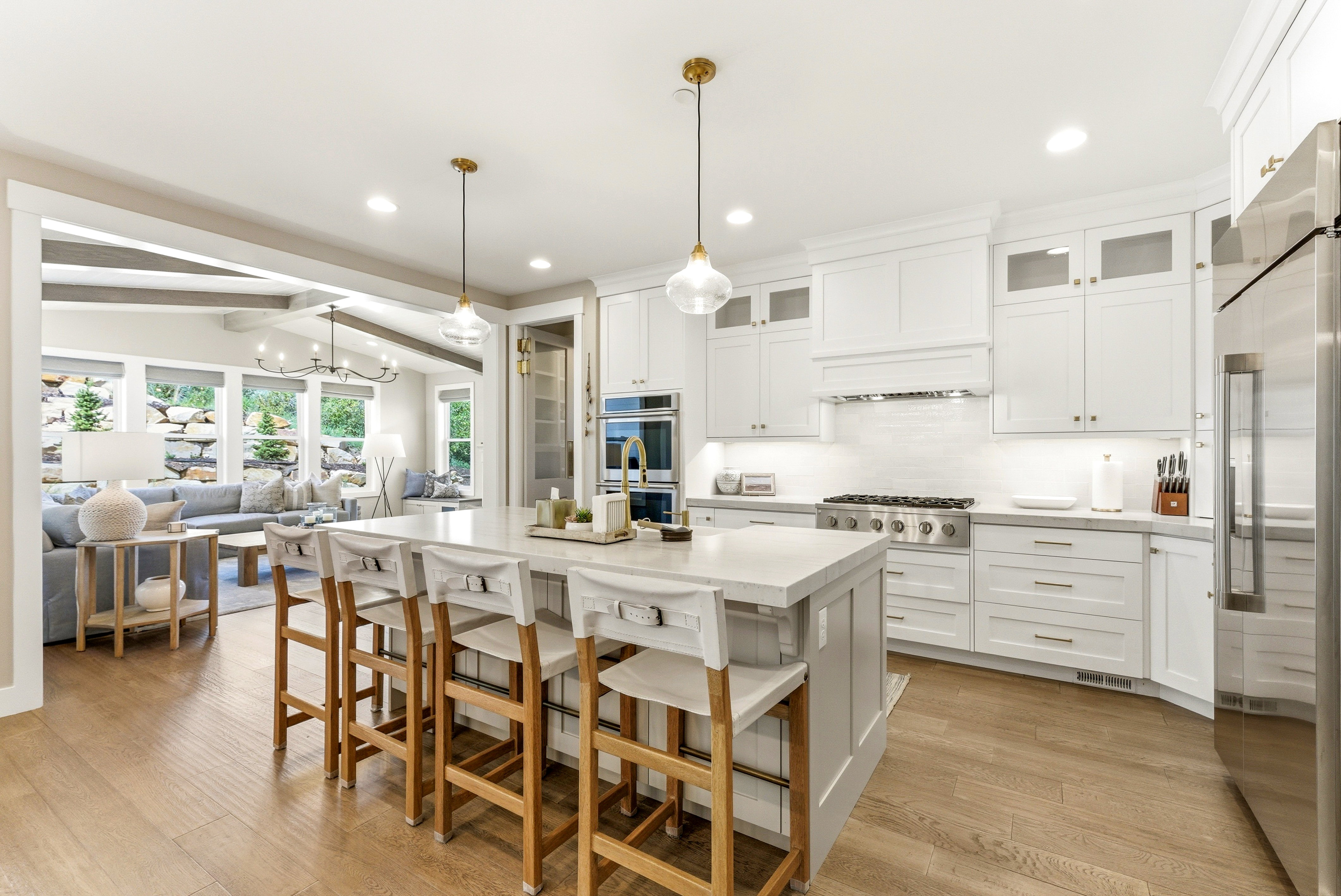 Kitchen featuring a large island with seating, stainless steel appliances, white cabinetry, and wood-finish flooring