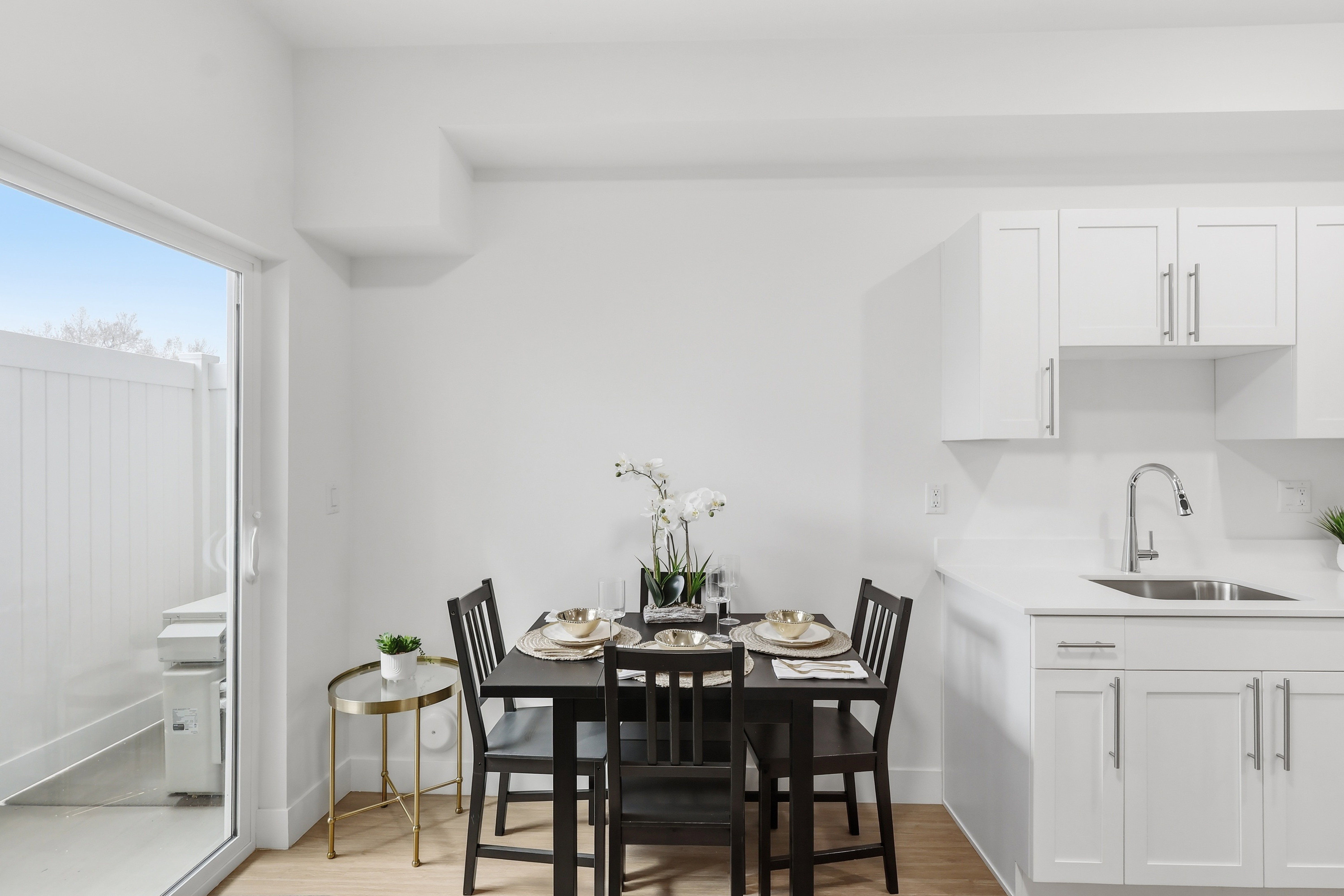Compact dining area featuring wood-finish flooring, white walls, and a sliding glass door leading to an outdoor space