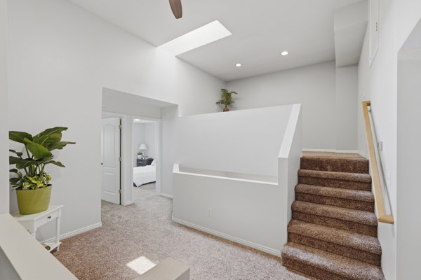Carpeted stairway with light wood handrail, recessed lighting, and a ceiling fan