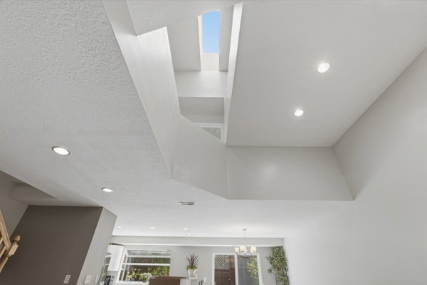 Multi-level ceiling design featuring recessed lighting and a skylight