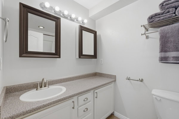 Bathroom vanity featuring a speckled countertop, white cabinetry with silver-tone hardware, and an undermount sink with a brushed nickel faucet