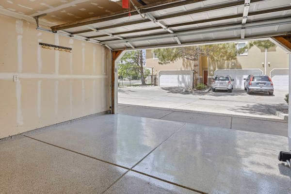 Spacious garage featuring a durable epoxy-coated floor, painted walls, and a visible garage door mechanism