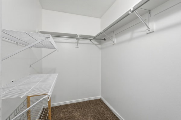 Walk-in closet featuring white wire shelving and hanging rods